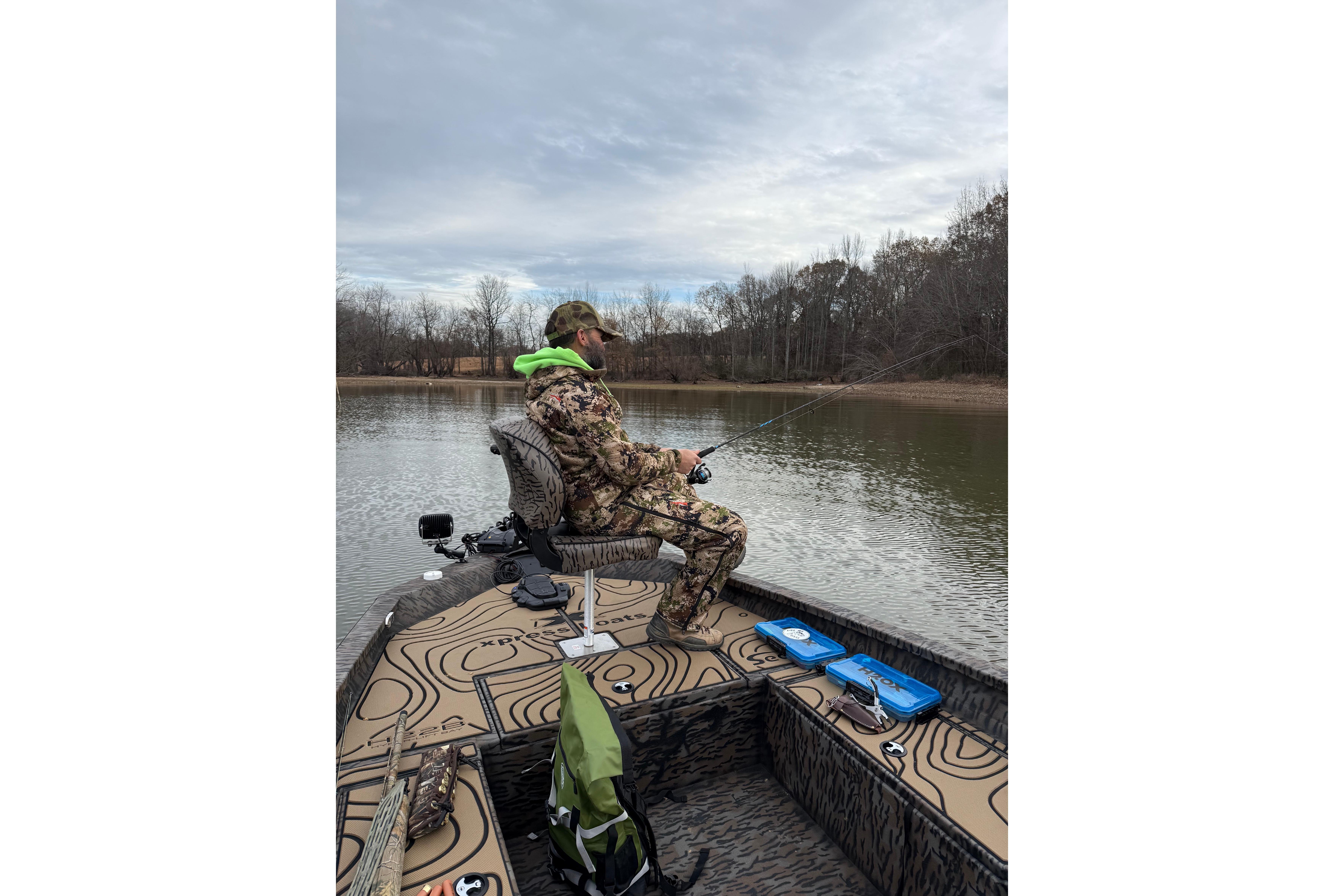 Person fishing on a 2025 Xpress H22B Bay boat in a serene lake setting.