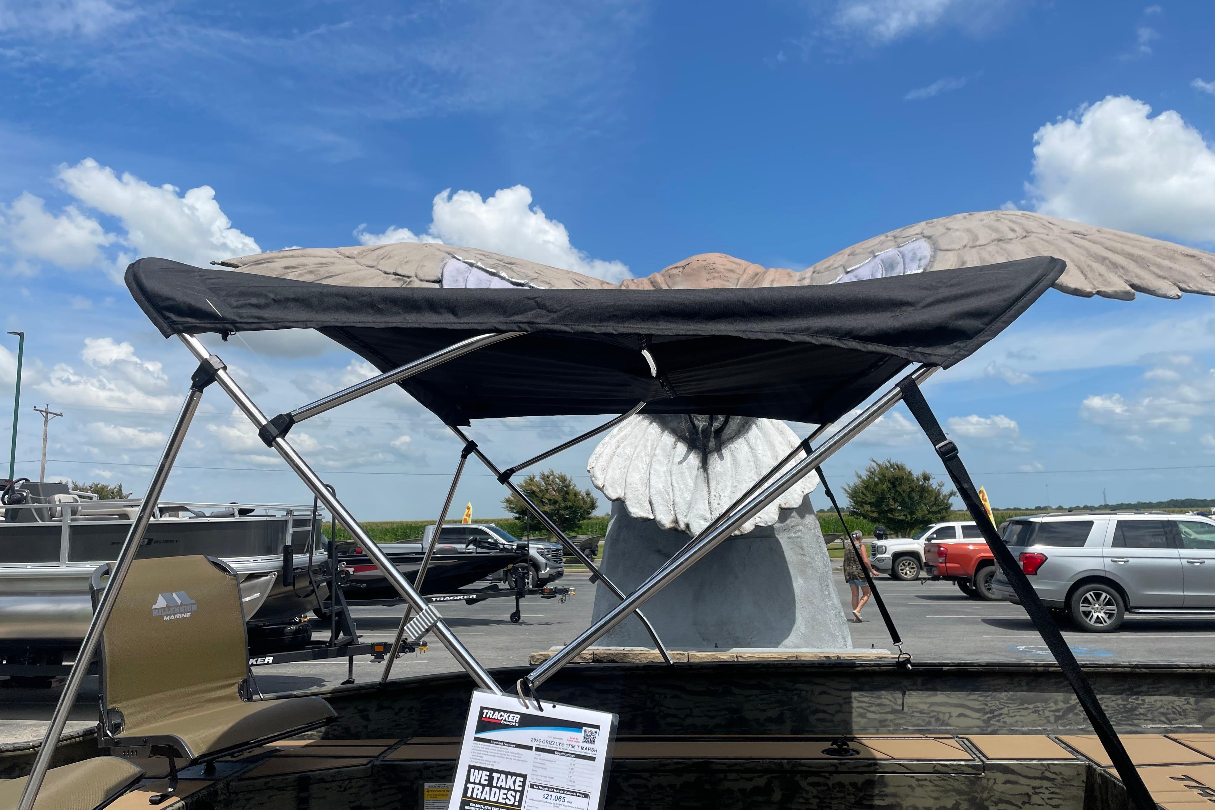 2026 Tracker Grizzly 1756 T Marsh boat with canopy, displayed outdoors under a blue sky.