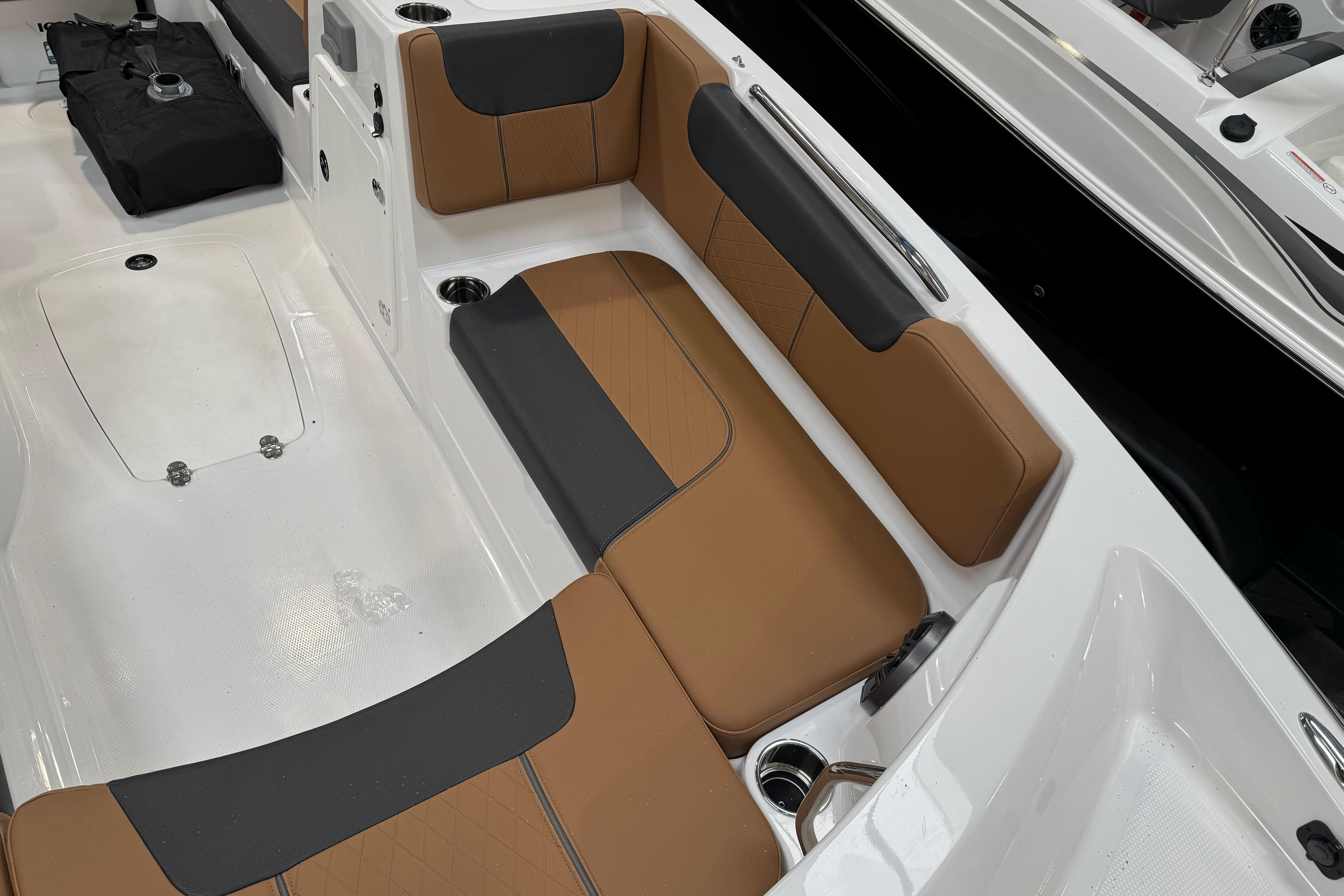 2026 Tahoe 2150 boat interior with tan and black seating, cup holders, and white flooring.