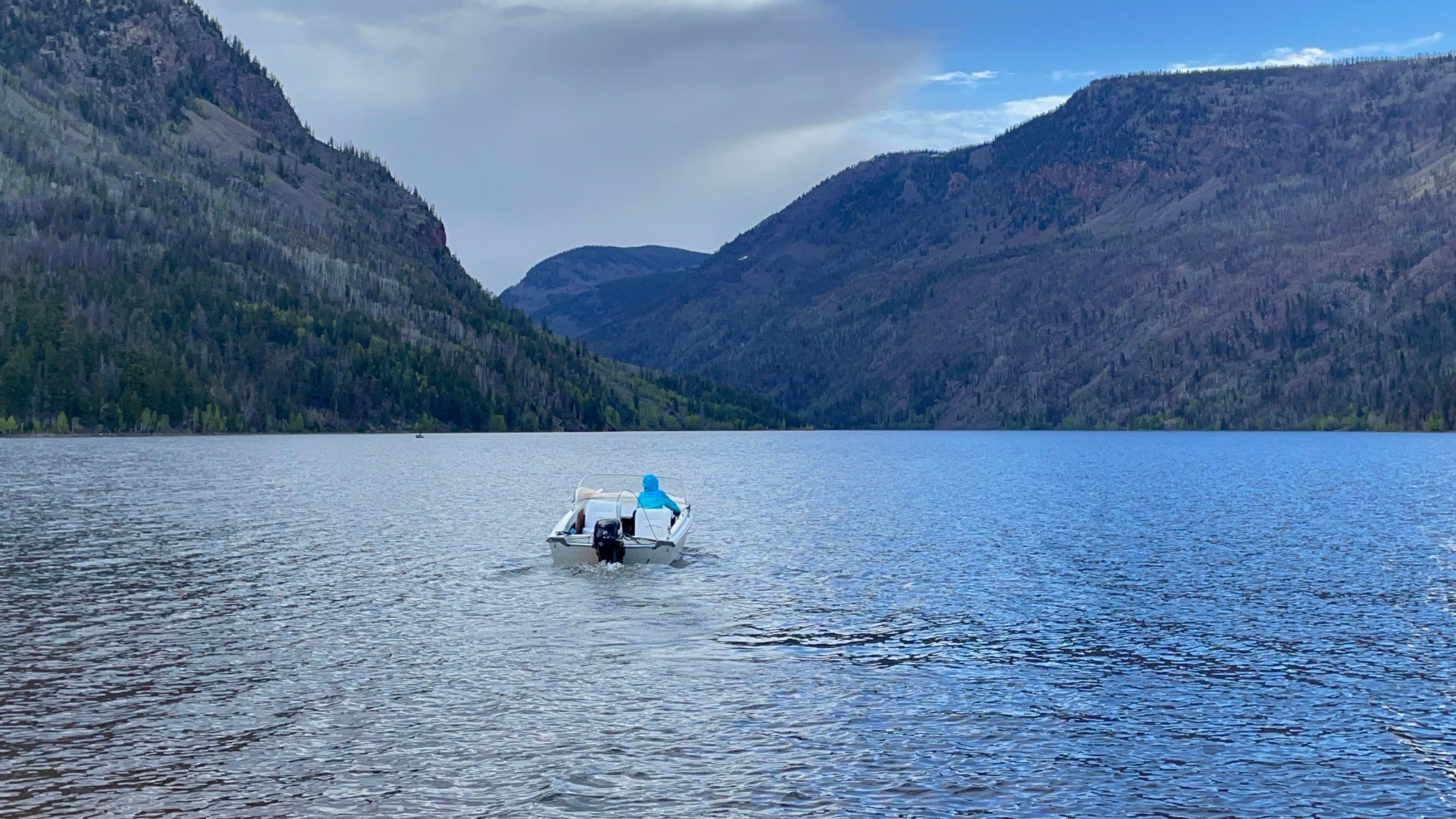 Boat on calm lake between forested mountains, Larsen 13 model from 1962.
