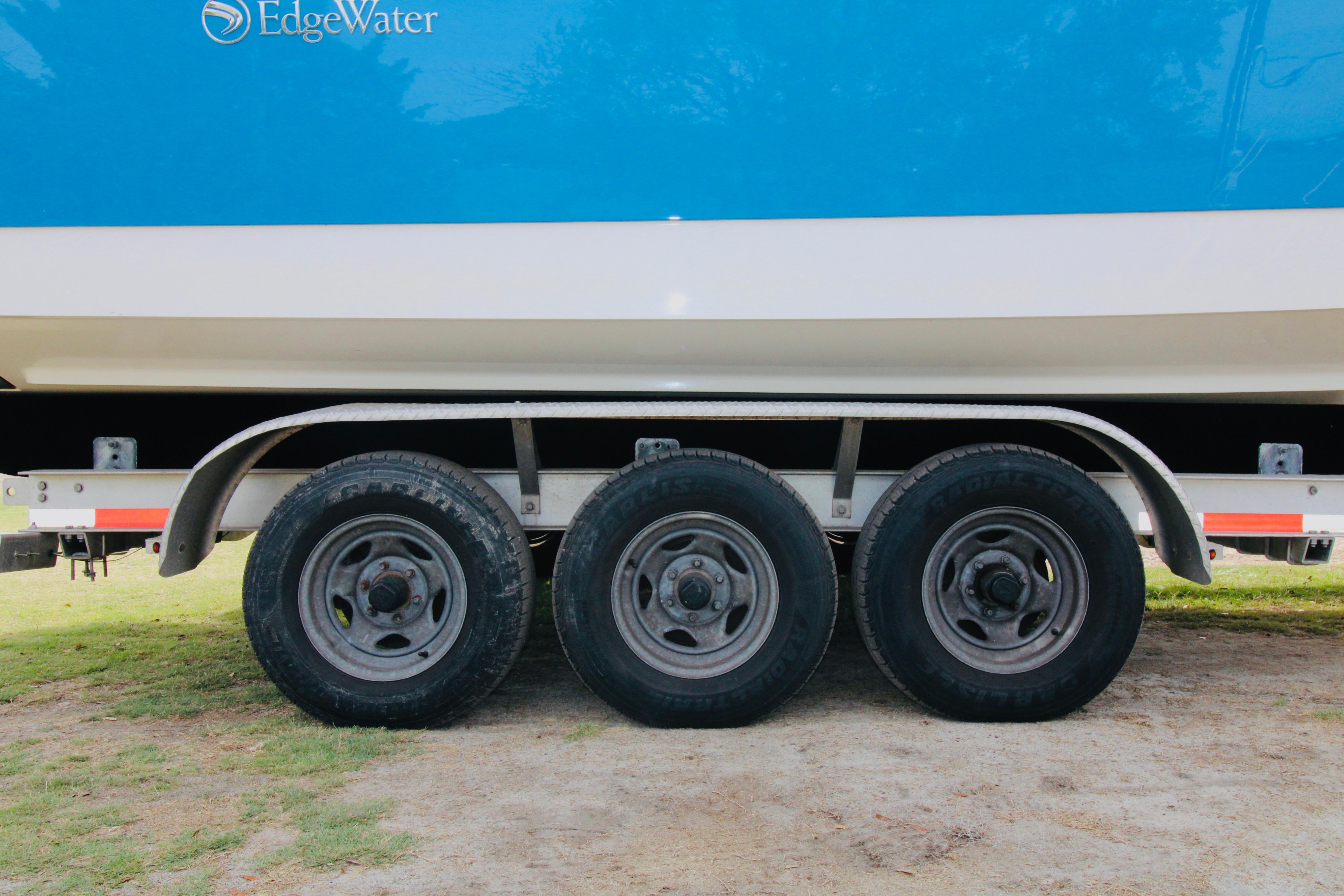Trailer with triple axles supporting a 2022 Edgewater 280CC boat.