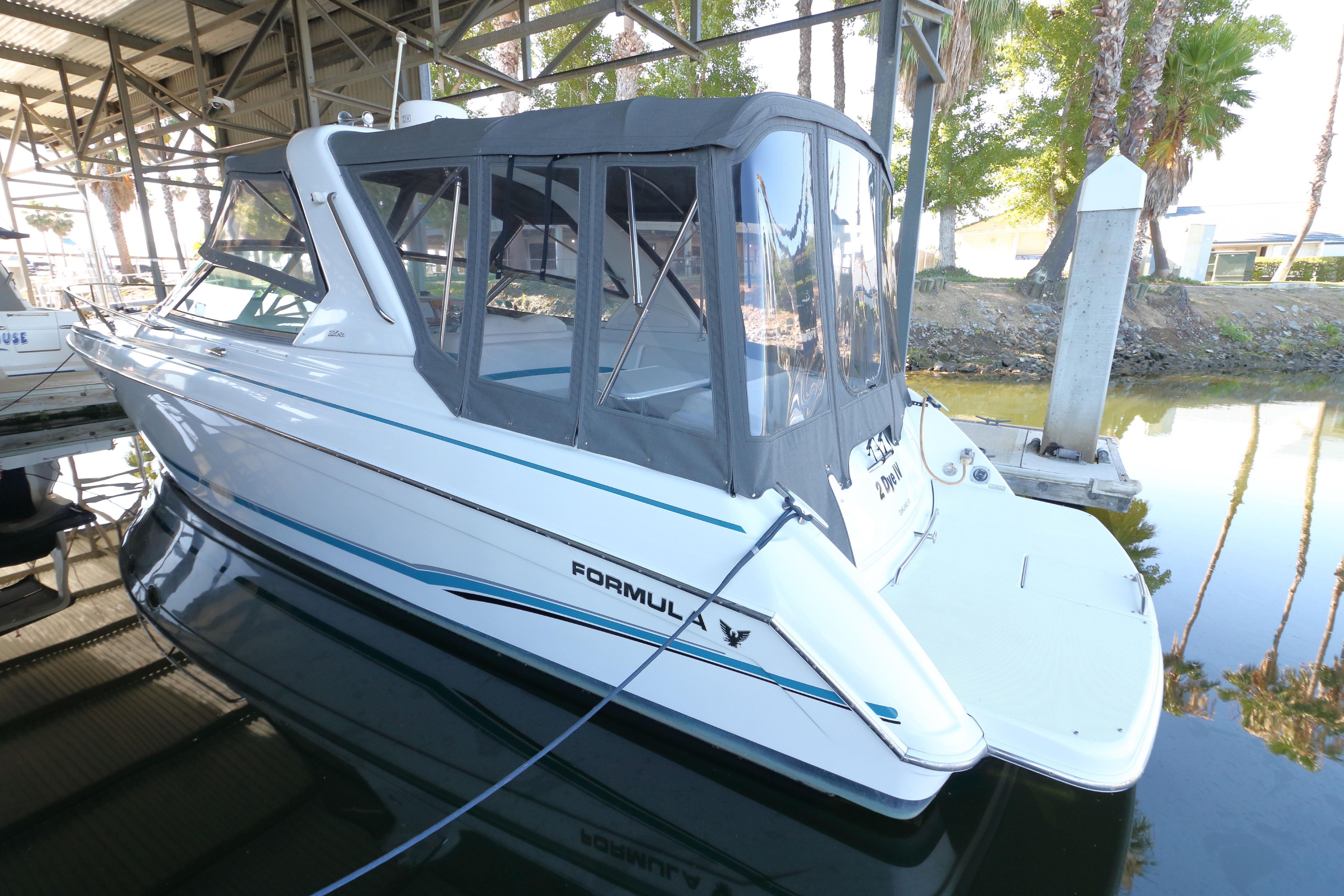 2006 Formula 330 Sun Sport boat docked under a canopy, featuring sleek design and enclosed cockpit.