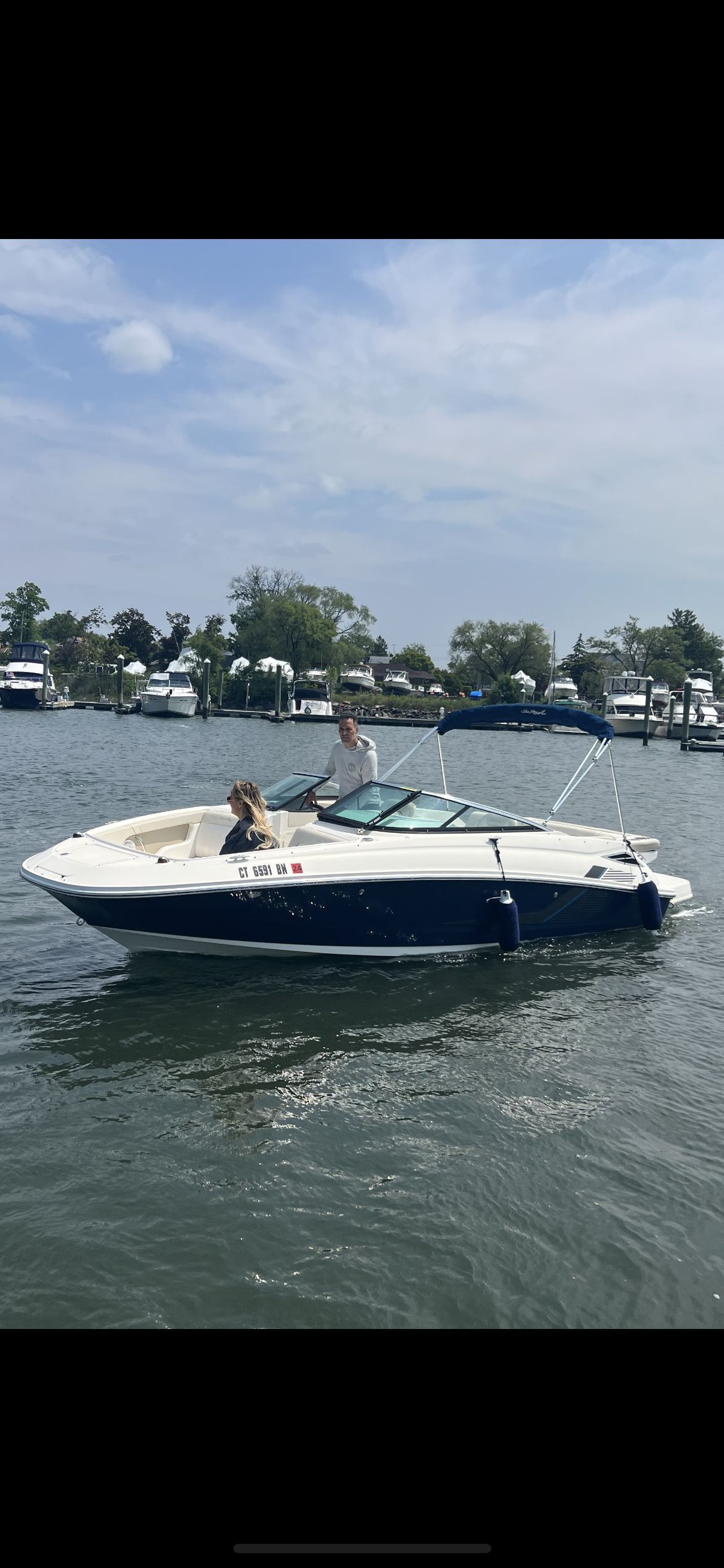A 2013 Sea Ray 220 Sundeck on calm water with two people on board.