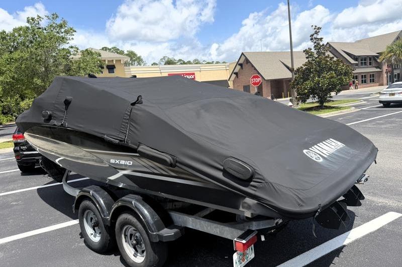 2017 Yamaha Boats SX210 covered on trailer in parking lot under blue sky.