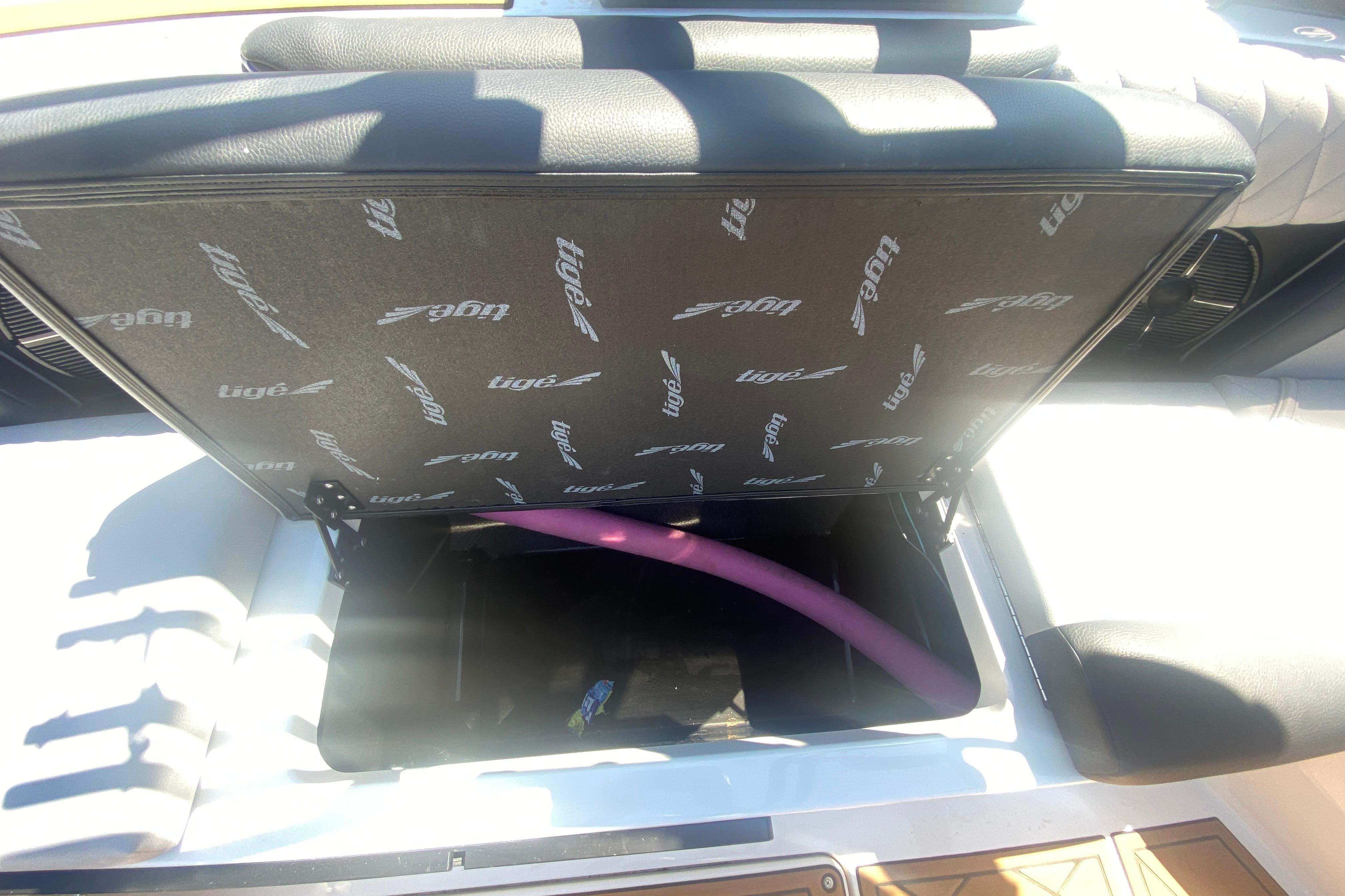Open storage compartment in 2021 Tigé Z3 boat with visible pink pool noodle.