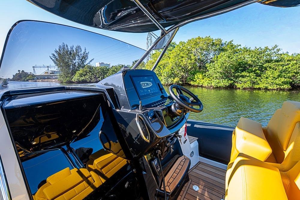 2025 SACS Strider 11 boat cockpit with modern controls and yellow seating on a sunny day.