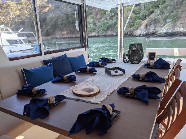 Elegant dining setup on a Bali 4.8 yacht, featuring blue napkins and scenic water views.