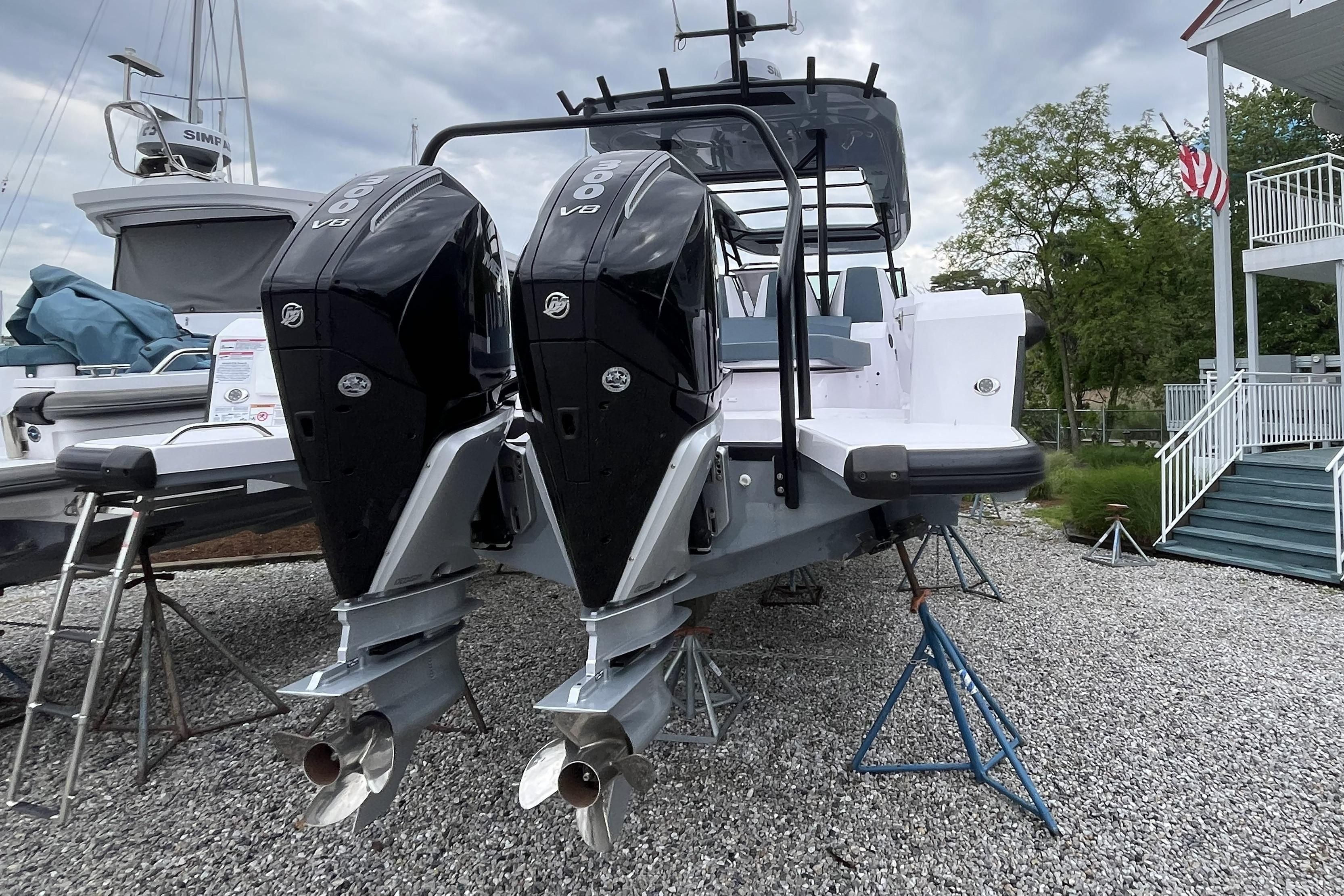 2025 Axopar 37 Sun-Top with dual outboard engines on display, parked on gravel.