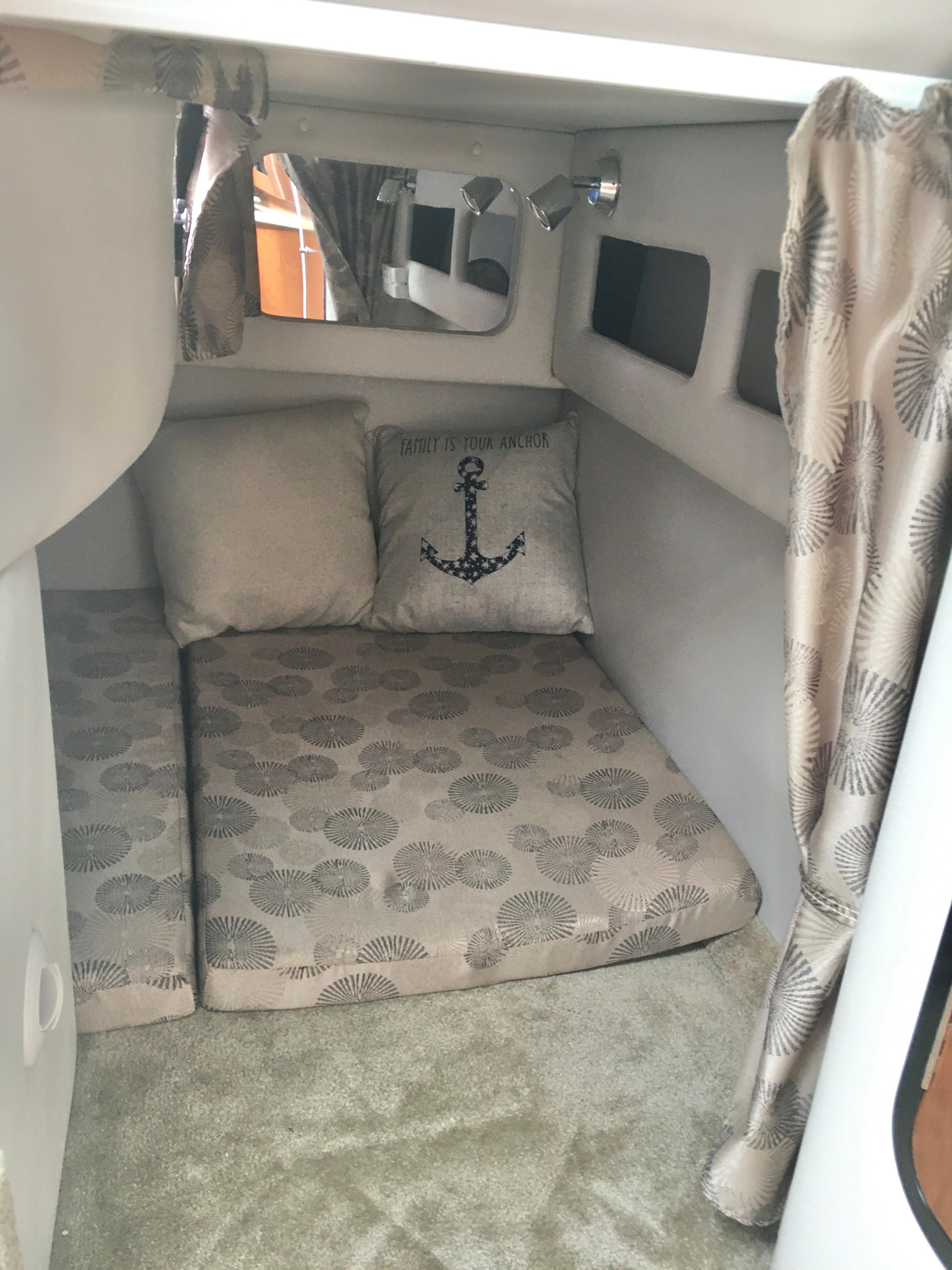 2018 Crownline 264 CR cabin interior with anchor-themed decor and patterned cushions.