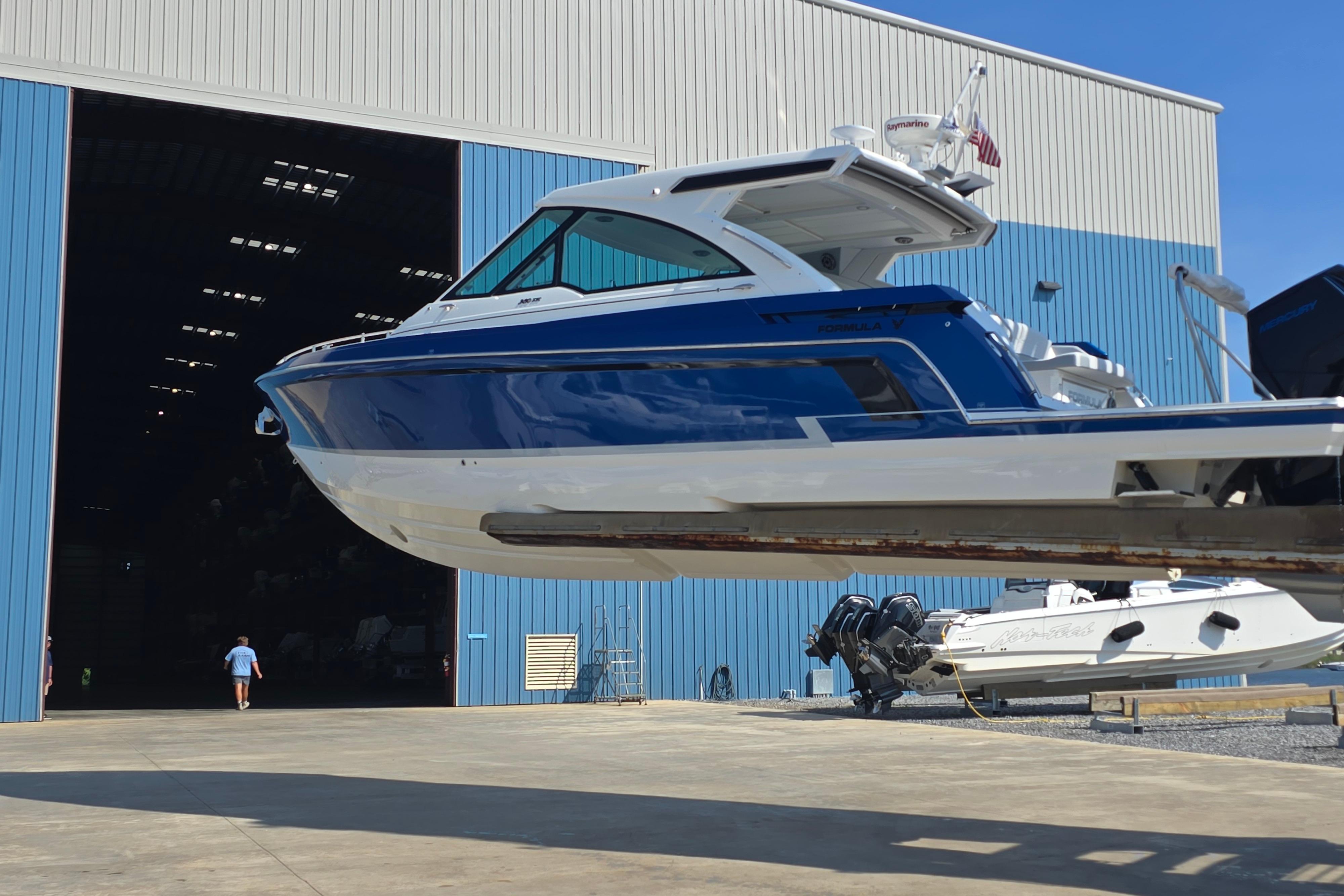 2025 Formula 380 Super Sport Crossover OB boat outside a large blue warehouse.