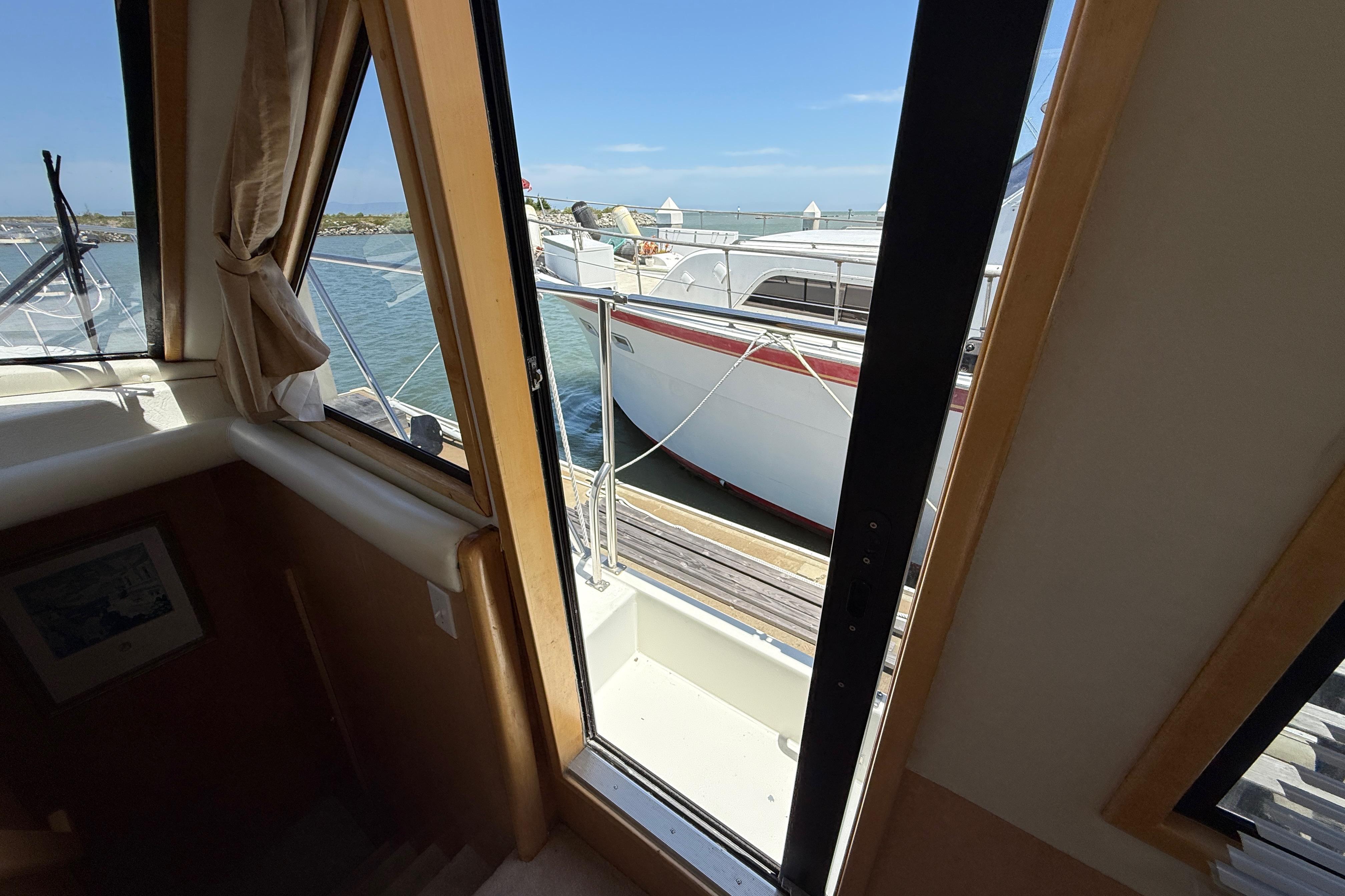 View from 1997 Navigator Pilothouse, showcasing marina and adjacent boat through cabin window.