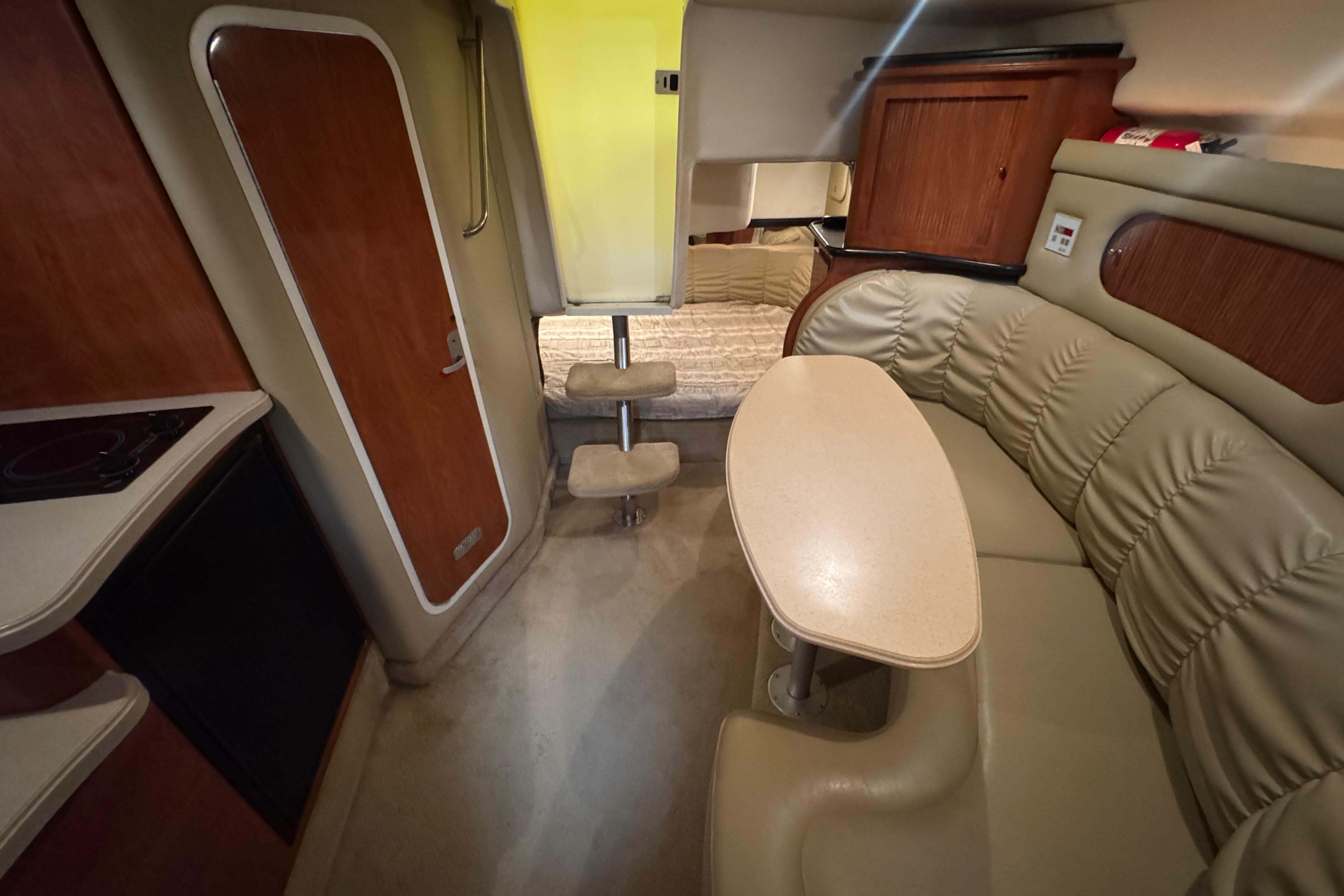2004 Rinker Fiesta Vee 312 cabin interior with seating, table, and kitchenette.