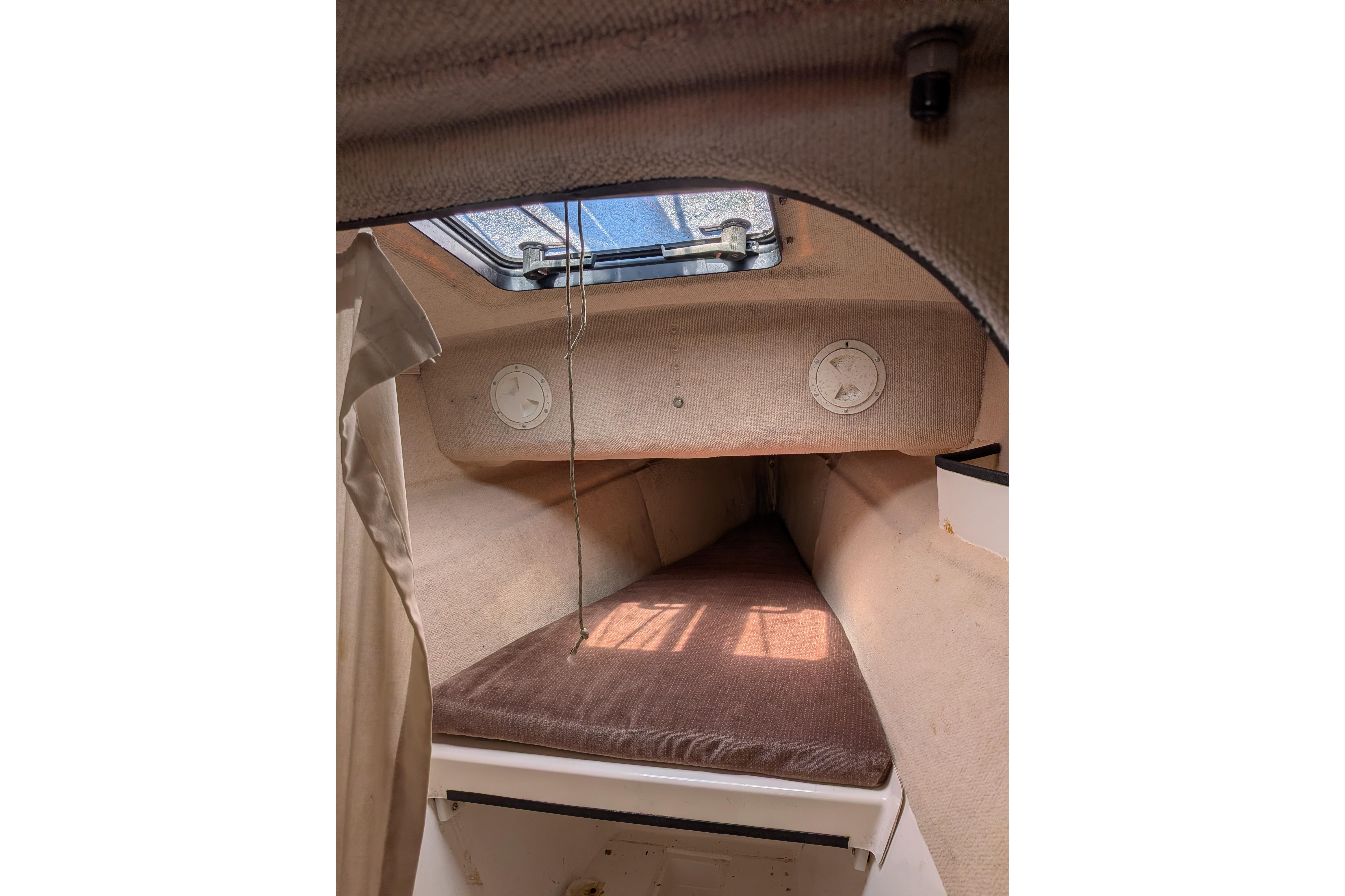 Interior cabin of a 1991 Corsair F-27 sailboat, featuring a cozy sleeping area.
