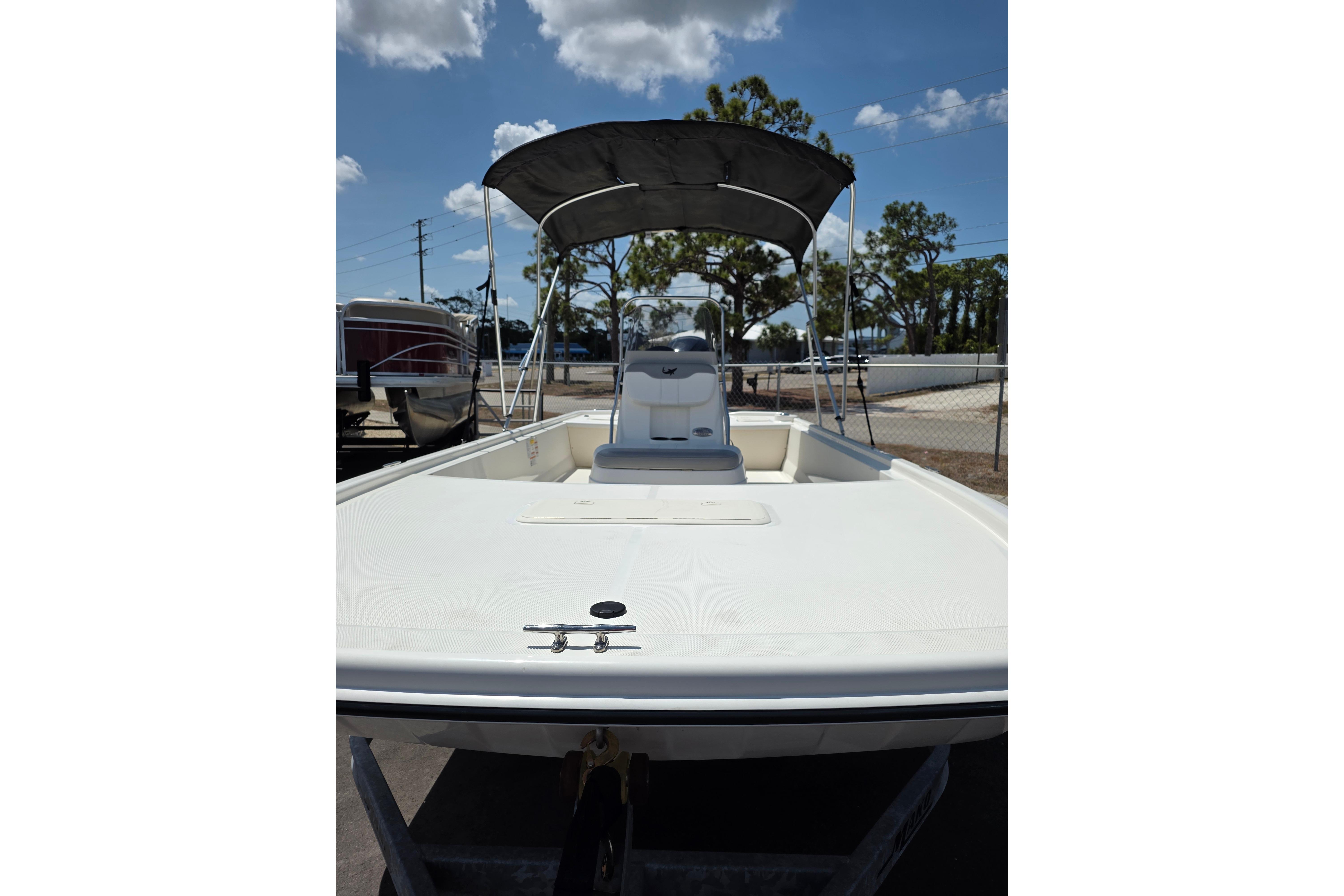 2018 Mako Pro Skiff 19 CC boat with canopy, parked outdoors under a blue sky.