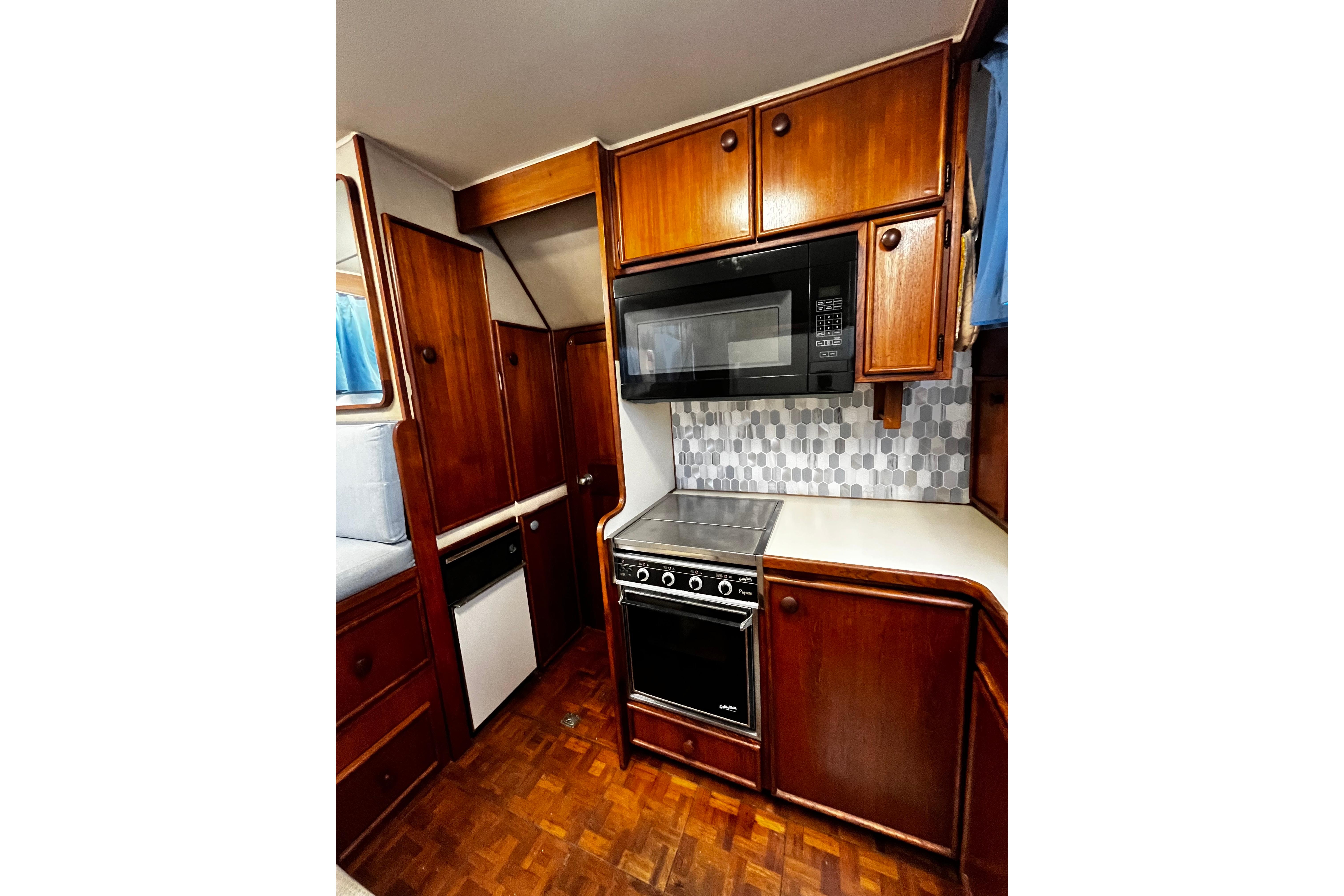1988 Chris Craft Constellation kitchen with wood cabinets, stove, and microwave.