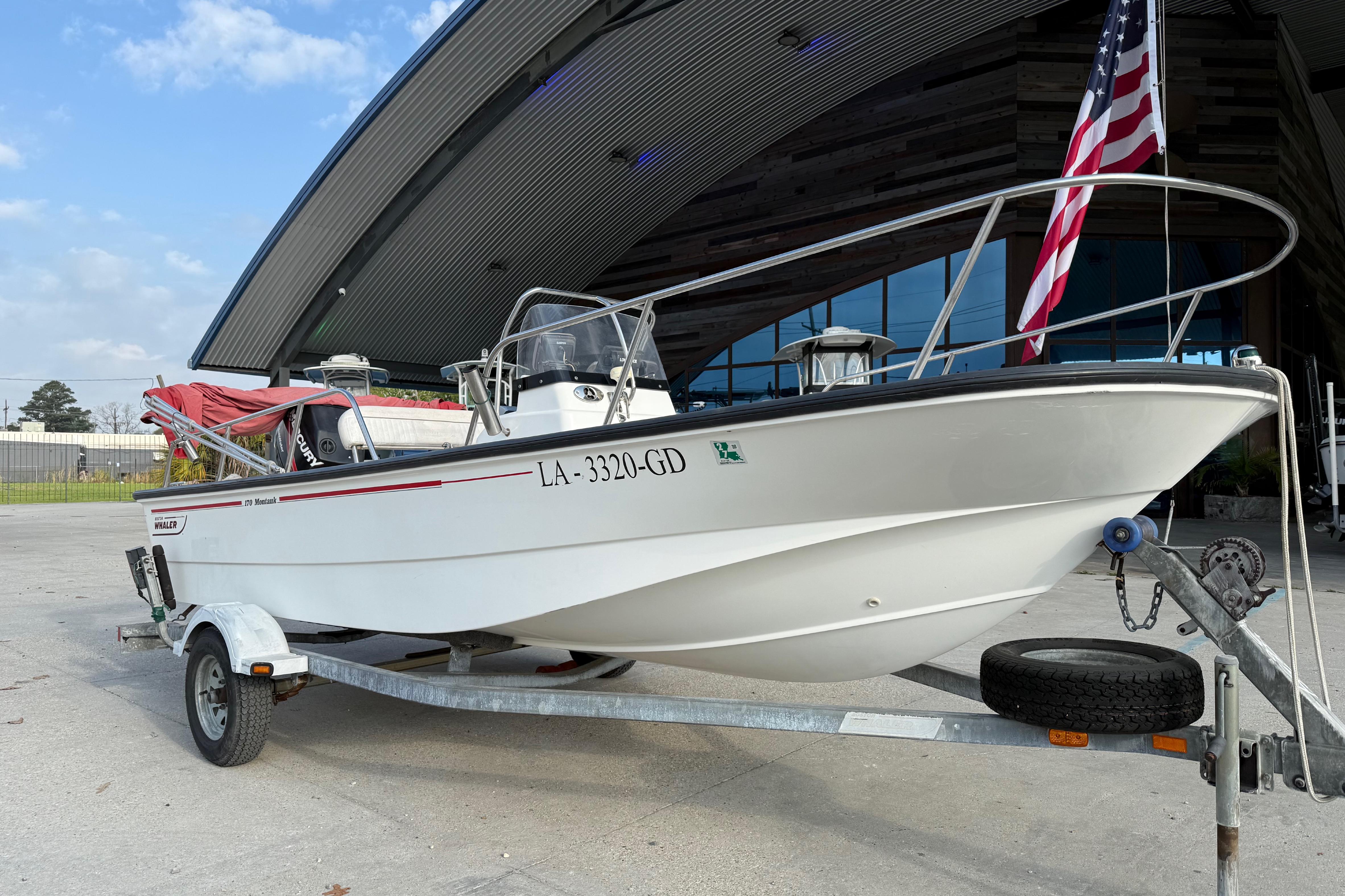 2005 Boston Whaler 17 Montauk boat on trailer, parked near modern building.