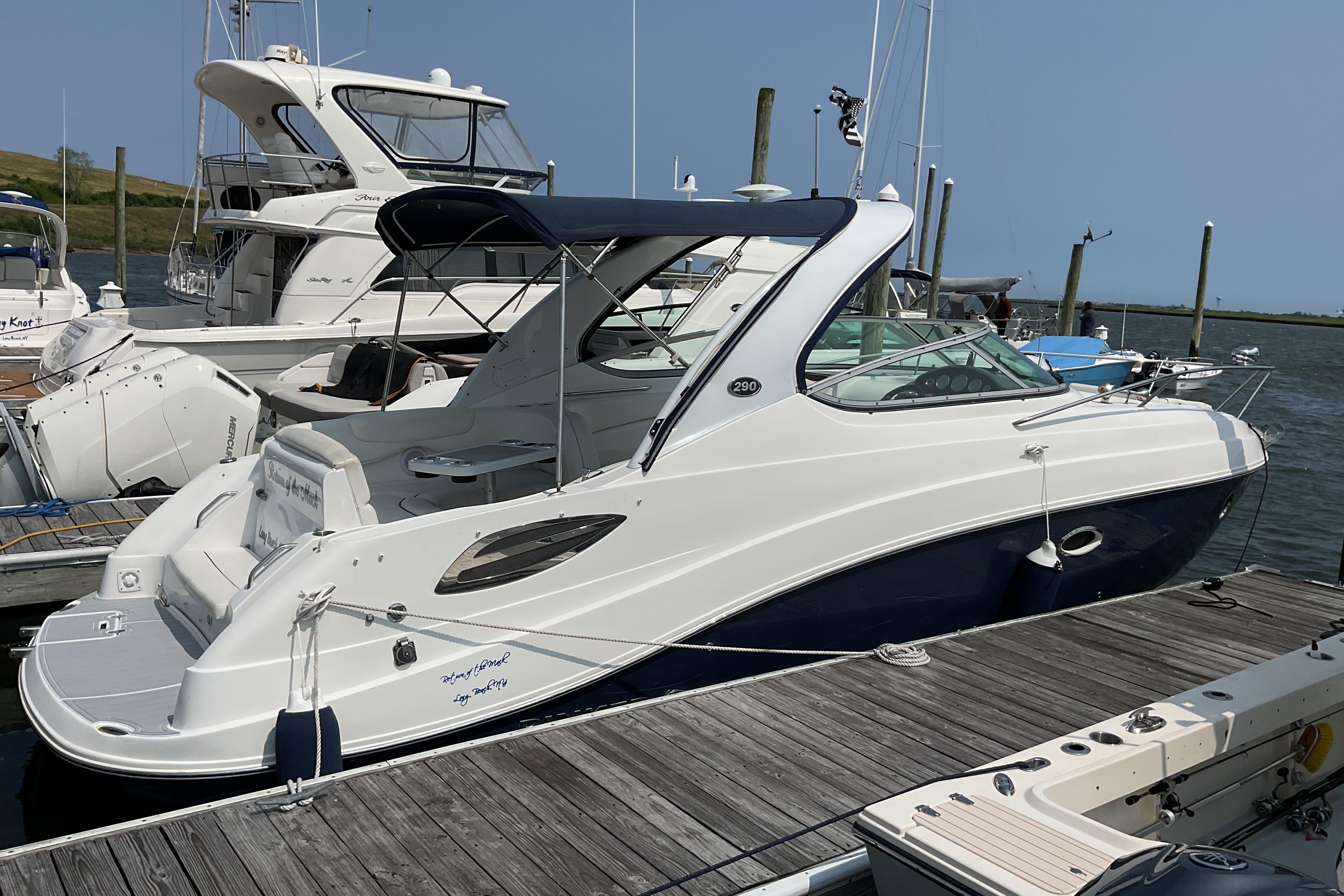 2013 Rinker 290 Express Cruiser docked at marina, featuring sleek design and blue accents.