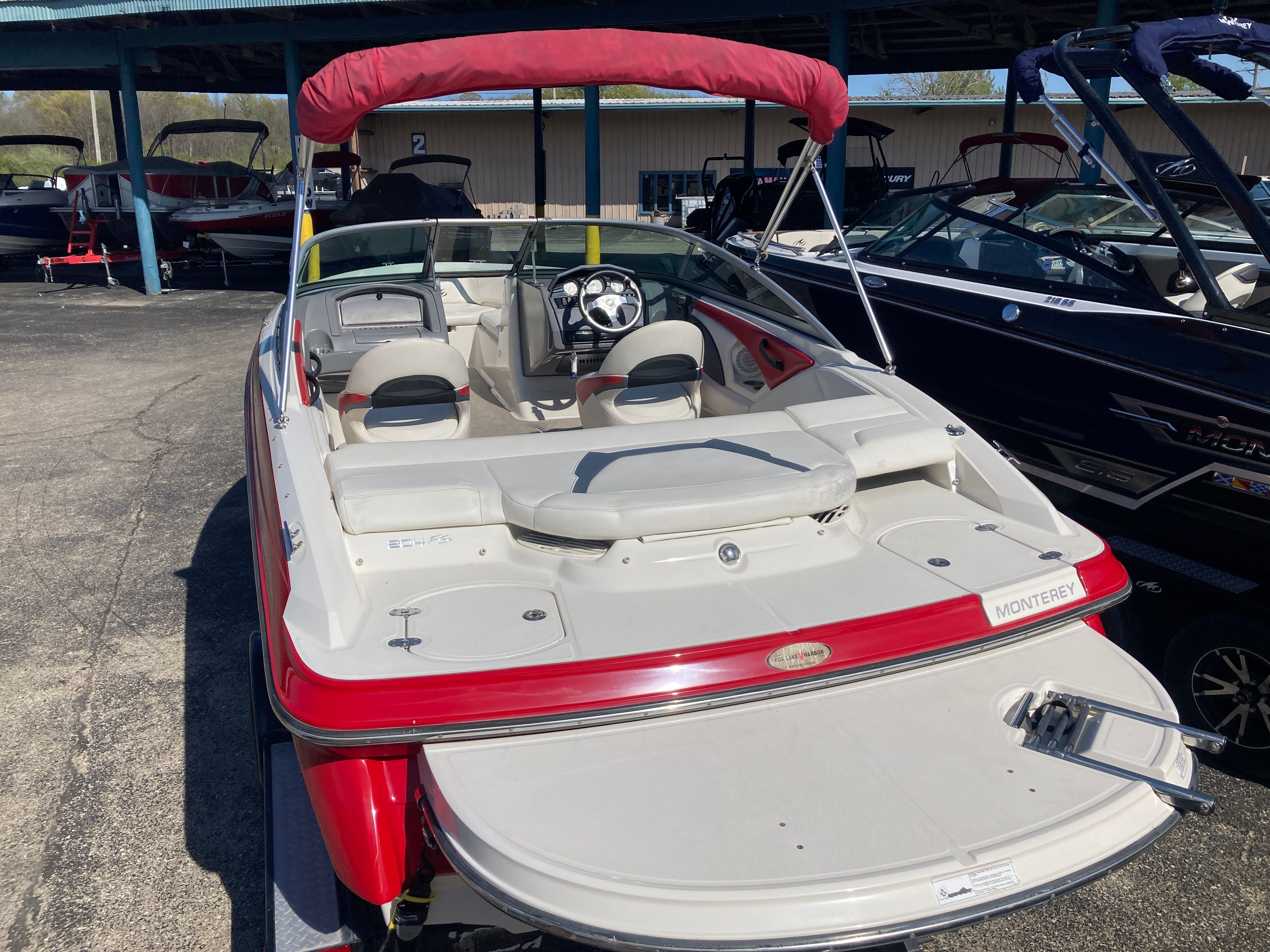2012 Monterey 204FS boat with red canopy in marina.