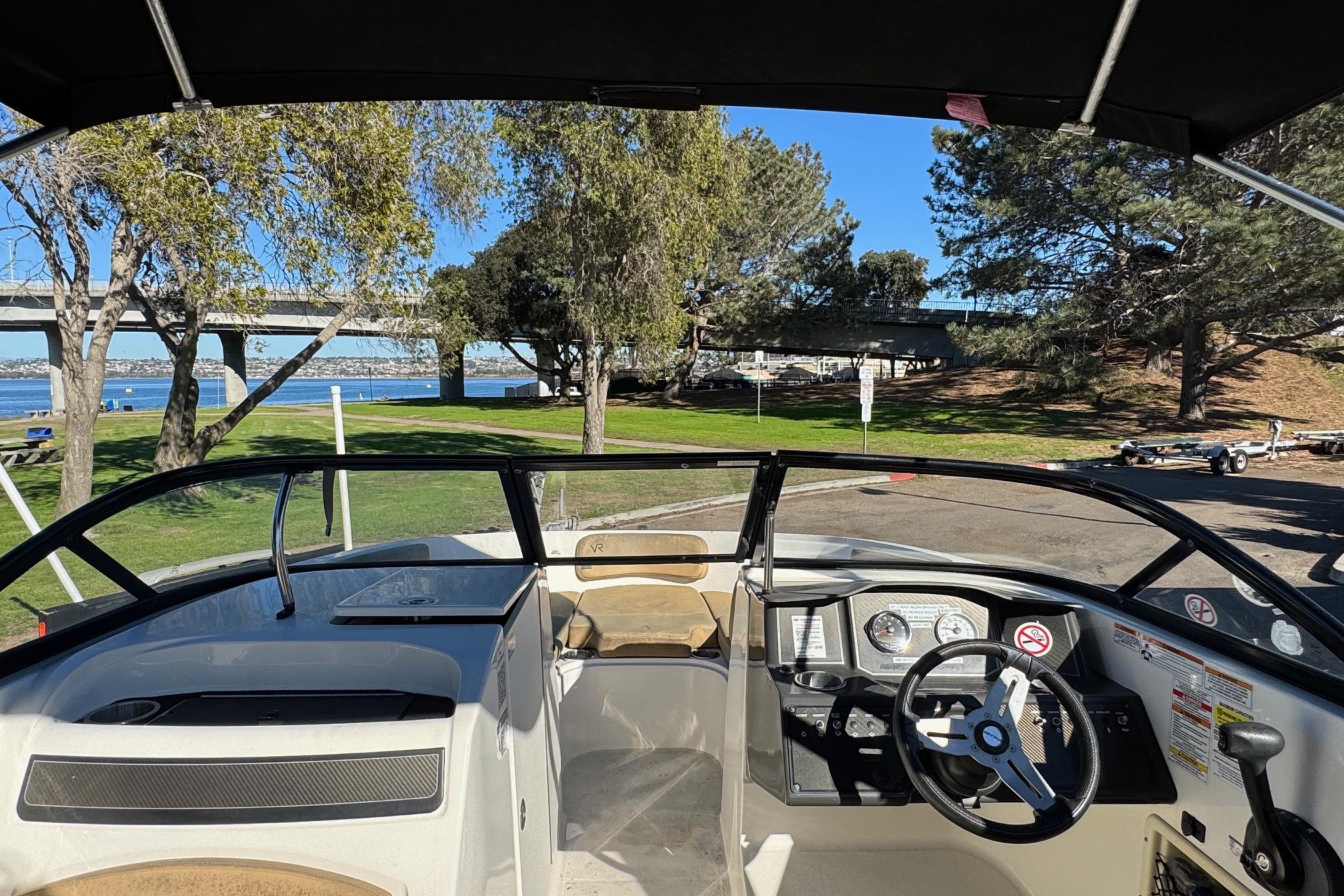 2022 Bayliner VR6 Bowrider OB interior with steering wheel, dashboard, and scenic park view.