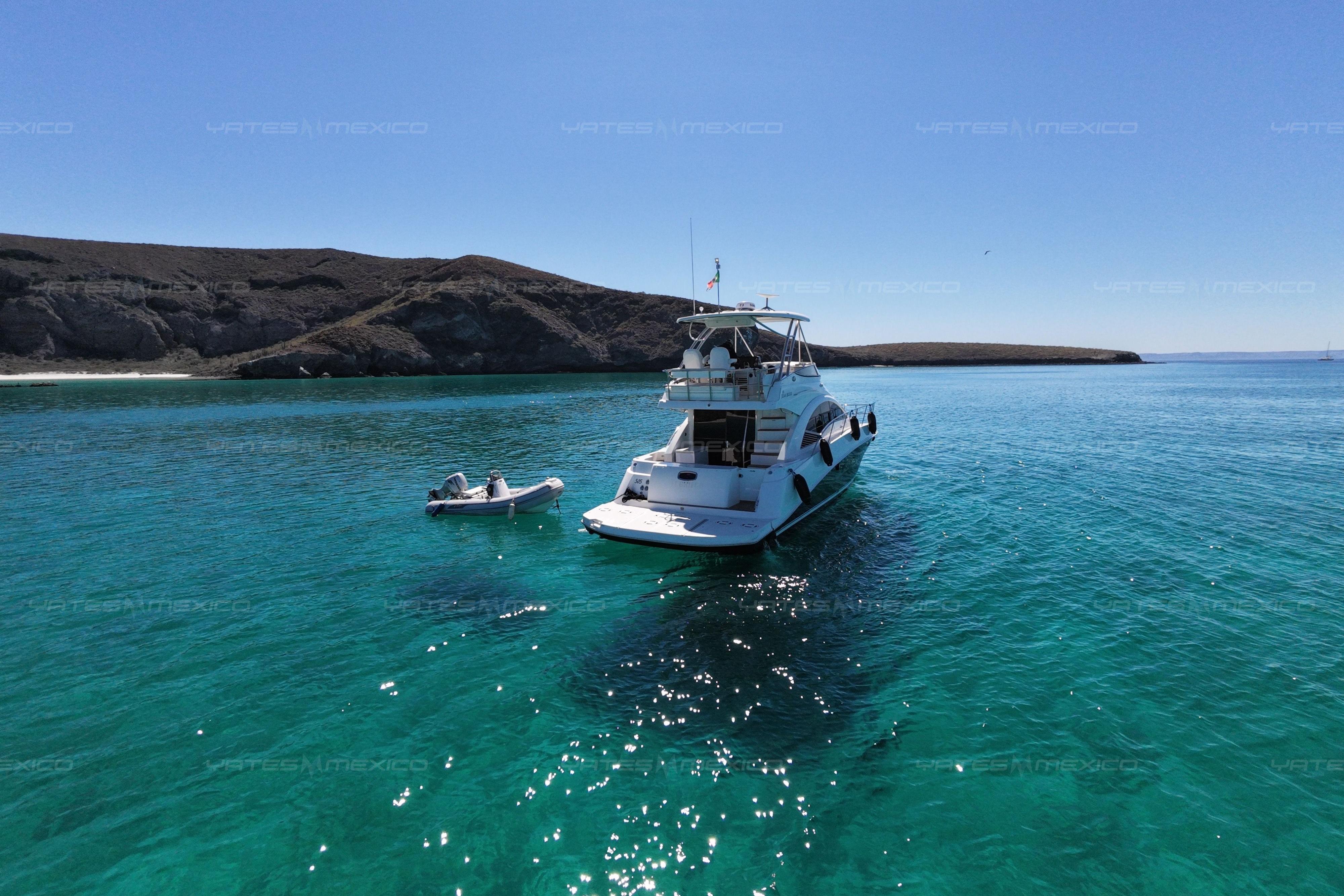 2008 Sea Ray 480 Sedan Bridge yacht anchored in clear turquoise waters near rocky coastline.