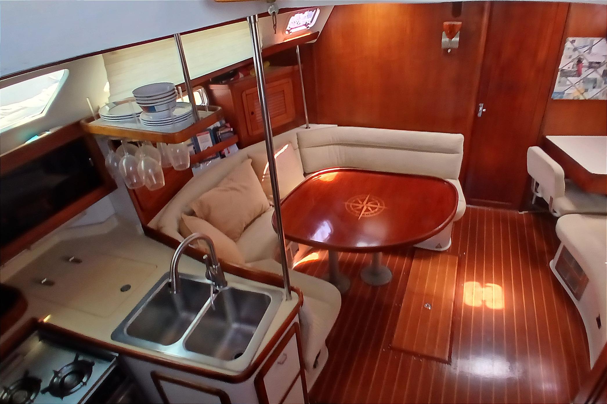 Interior of 1995 Catalina 42 MkII yacht with cozy seating and wooden dining table.