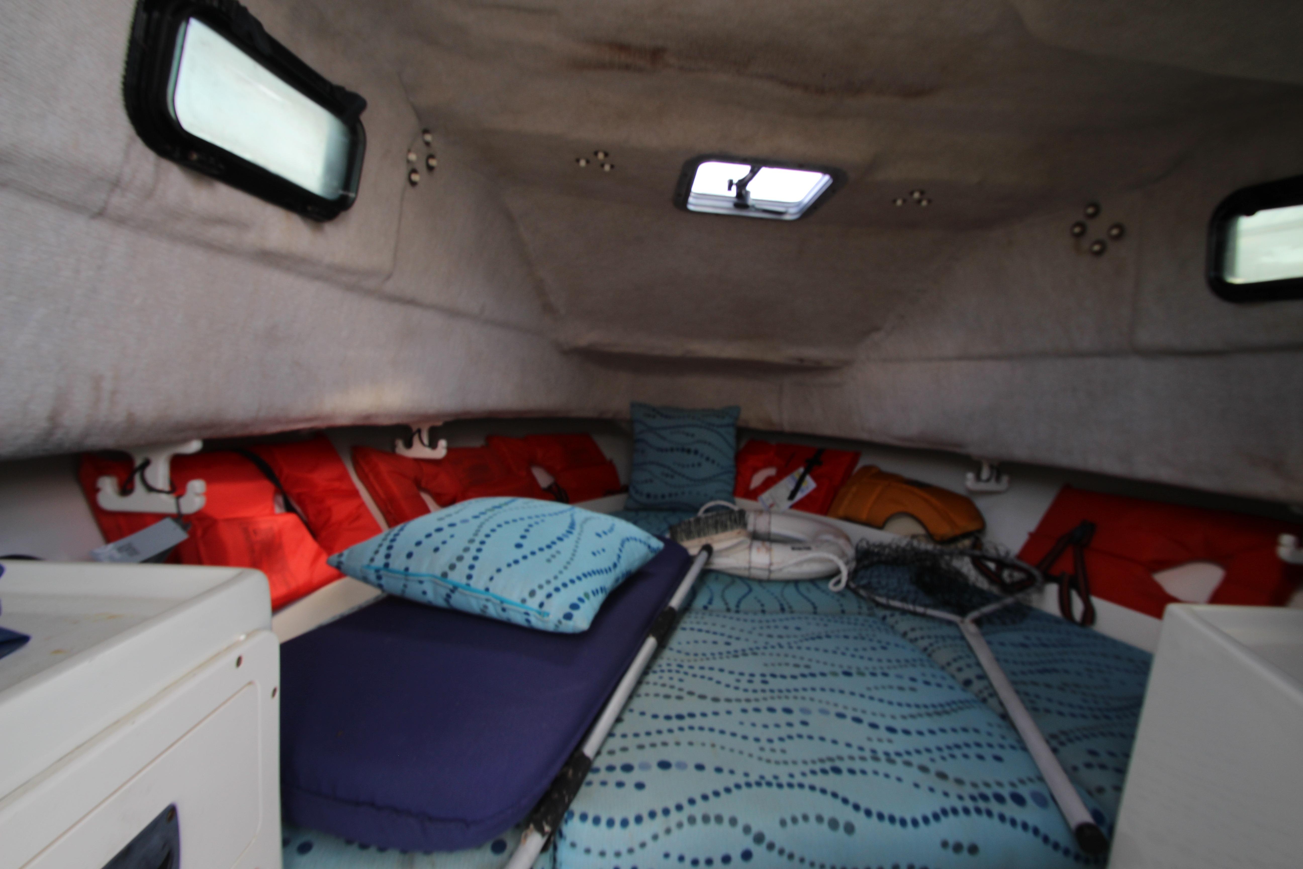 Interior cabin of 2002 Hydra-Sports 230 WA boat with bedding and fishing gear.