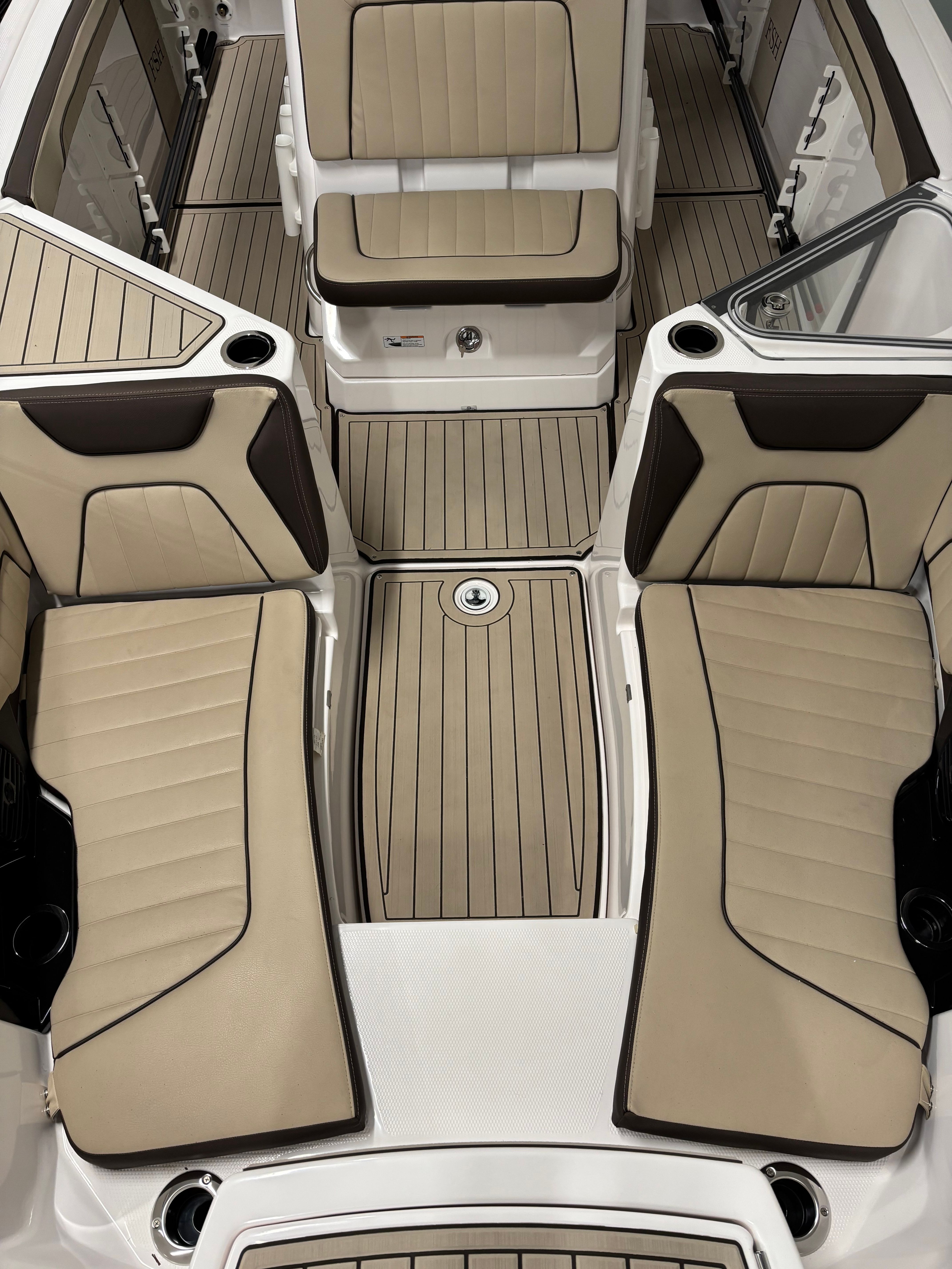 Interior of a Yamaha 222 FSH Sport E boat with beige upholstery and wood flooring.