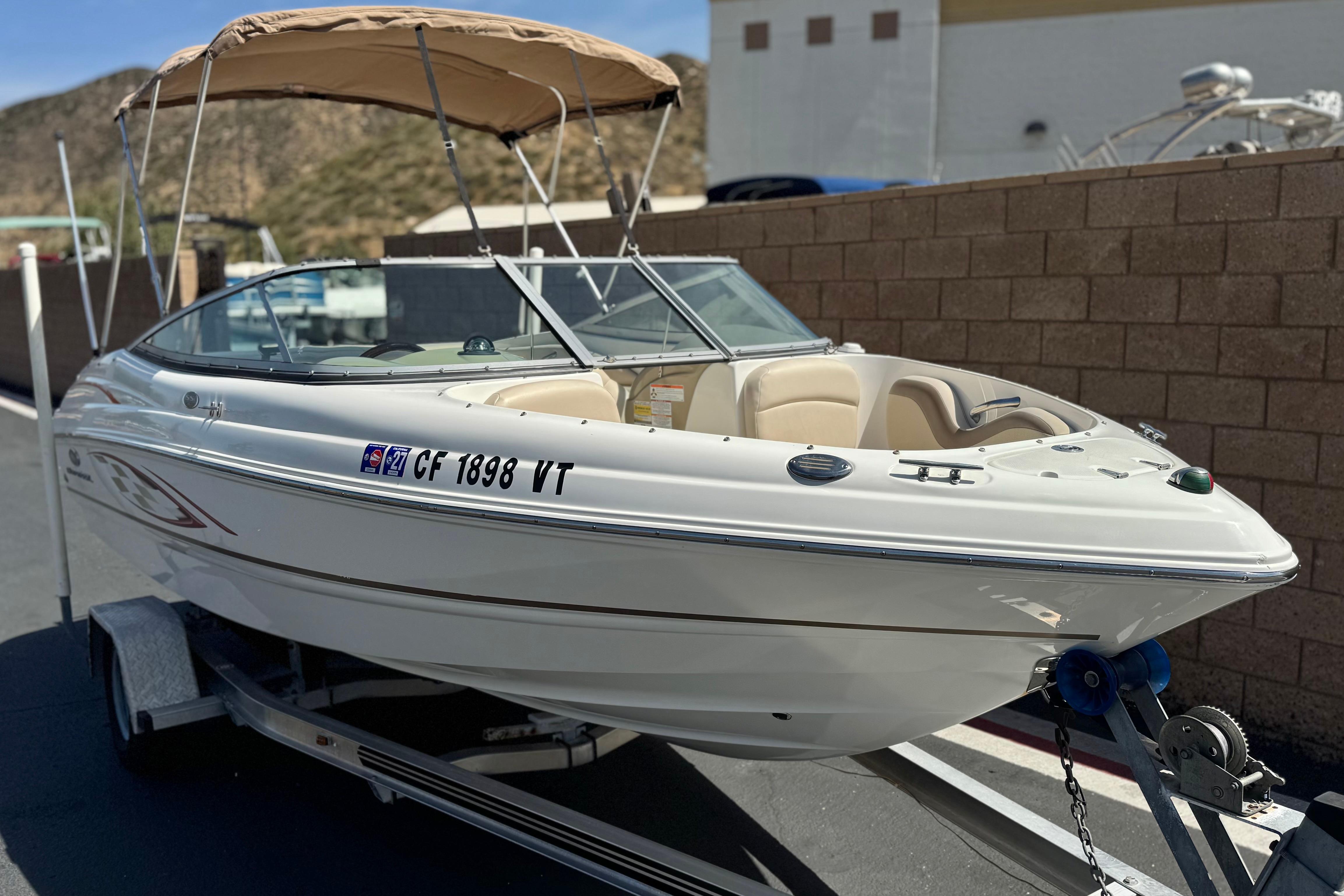 2006 Chaparral 190 SSi boat on trailer with beige canopy, parked outdoors.
