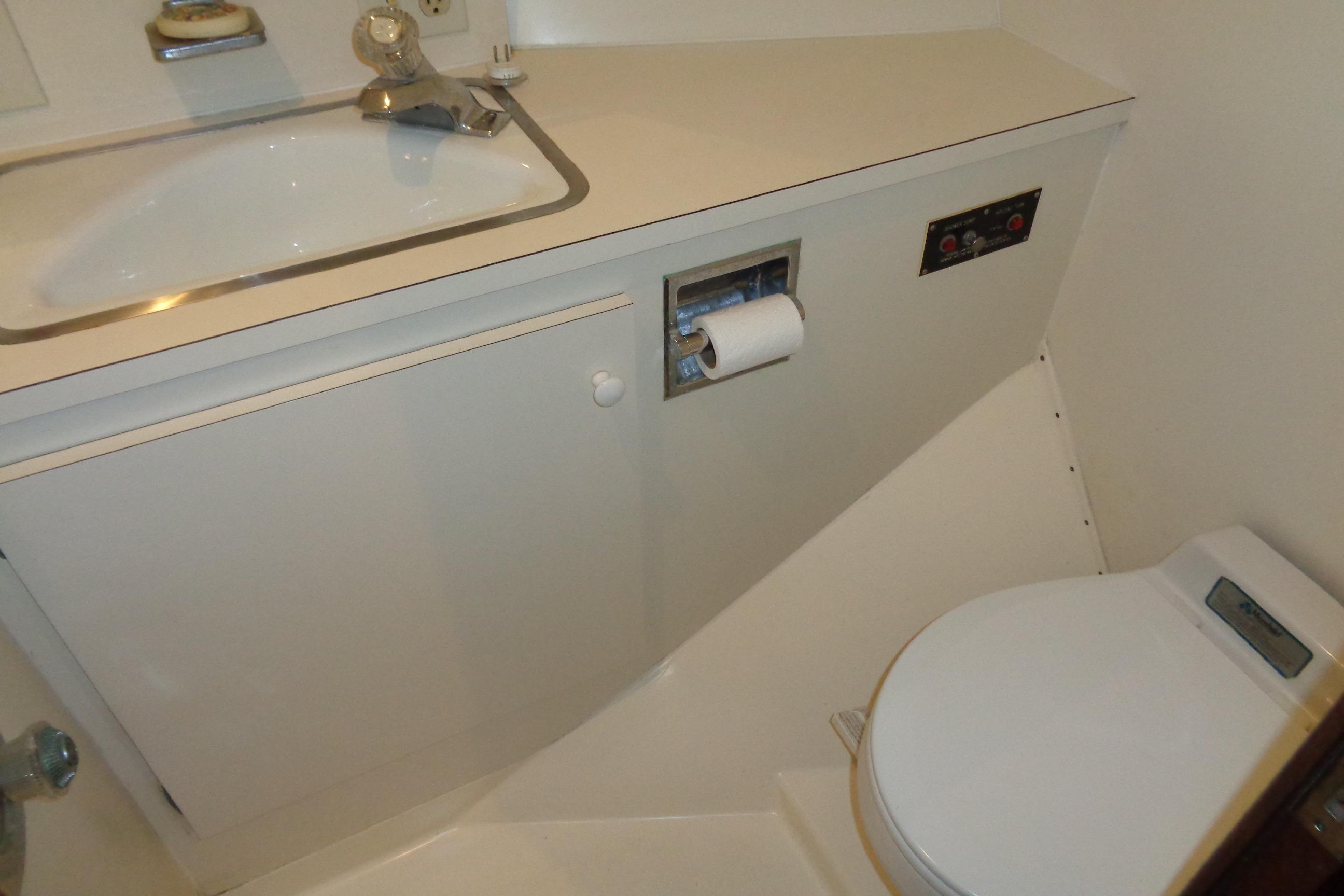 Bathroom interior of 1981 Hatteras 48 Cockpit Motor Yacht, featuring sink and toilet.