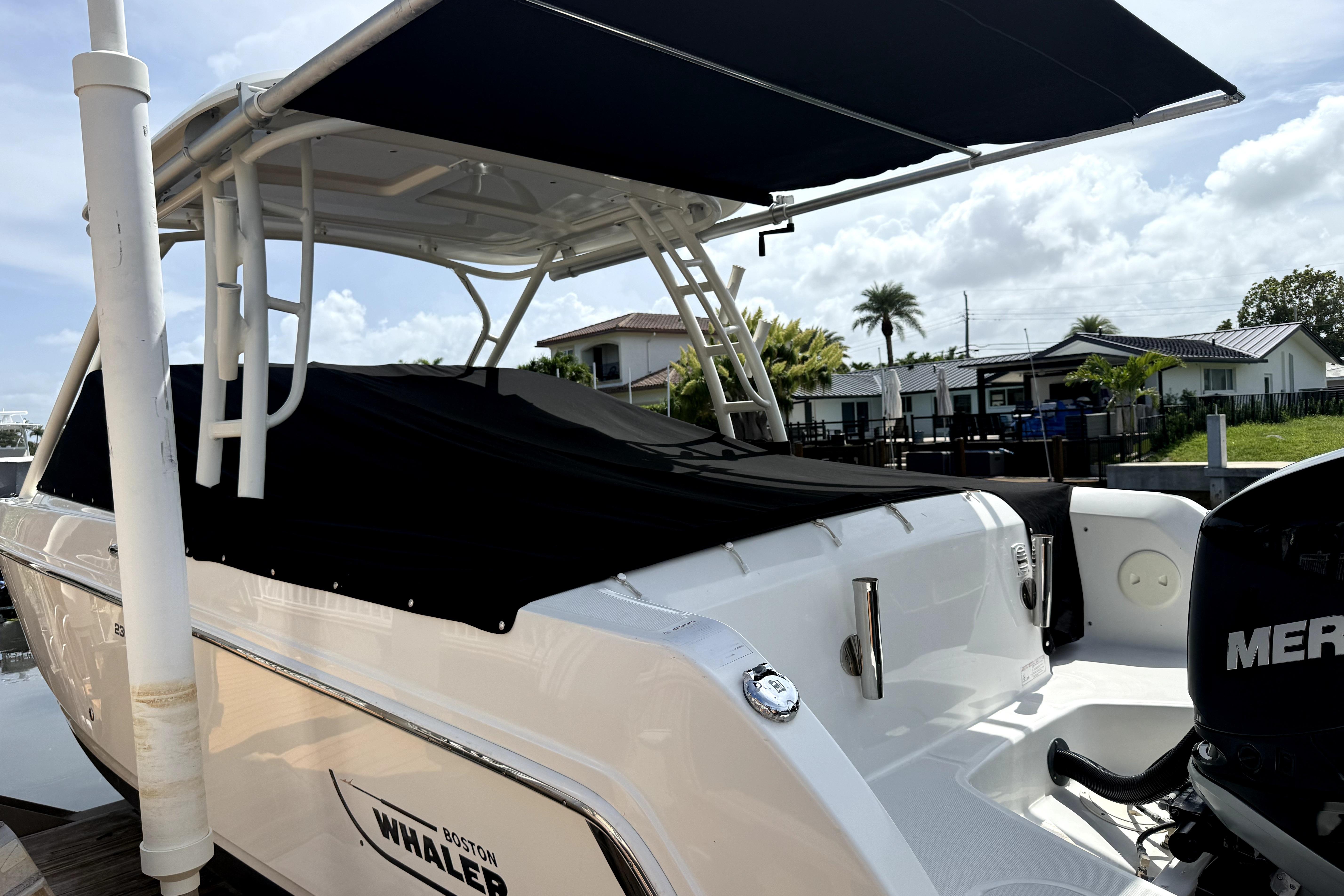 2018 Boston Whaler 230 Vantage boat docked with canopy and Mercury engine.
