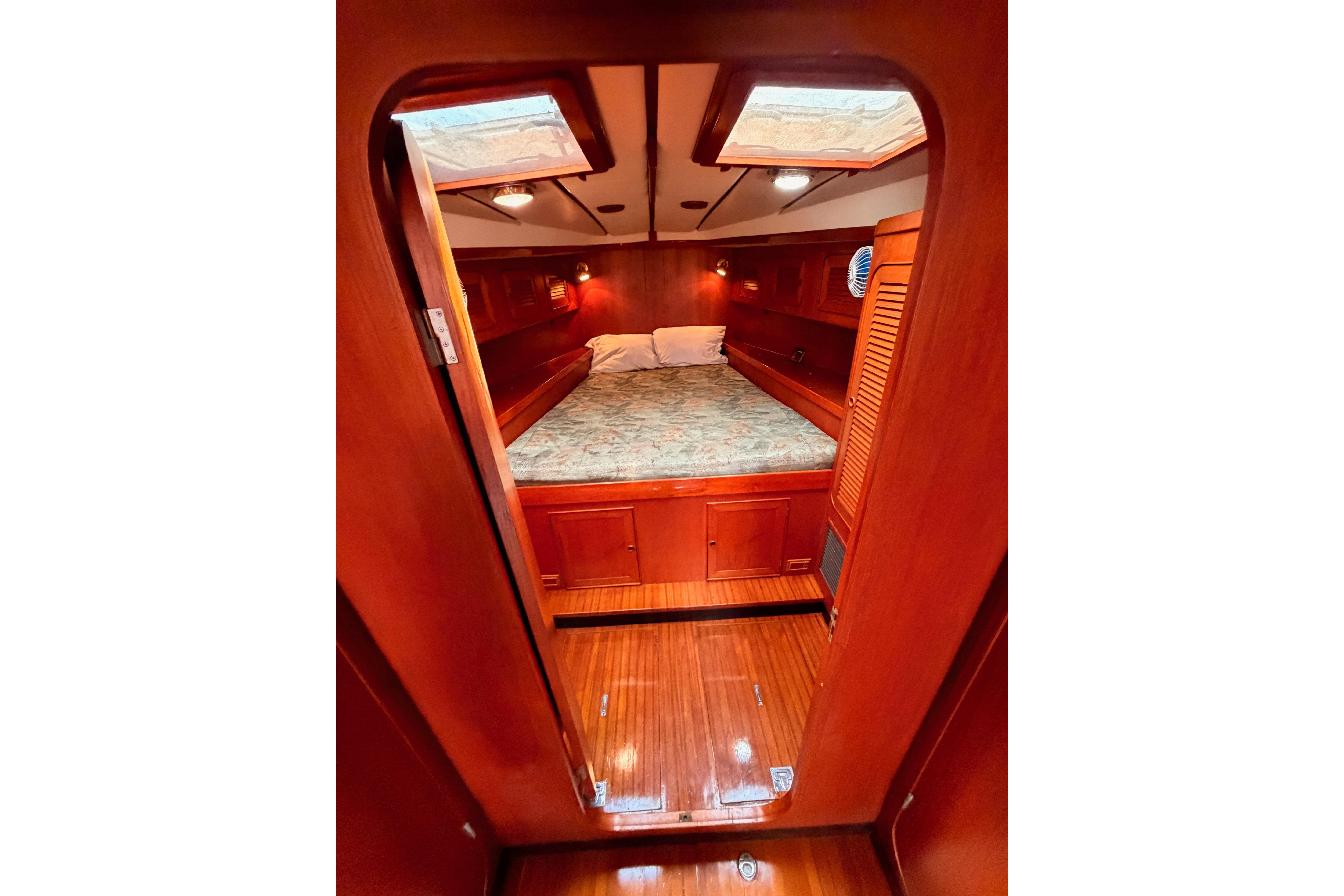 Cozy cabin interior of a 1991 Hylas 51 yacht with wooden finishes and a skylight.
