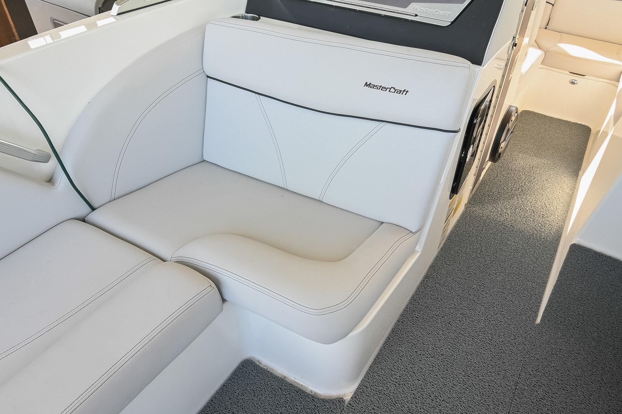 2018 MasterCraft X23 boat interior with white cushioned seating and carpeted flooring.