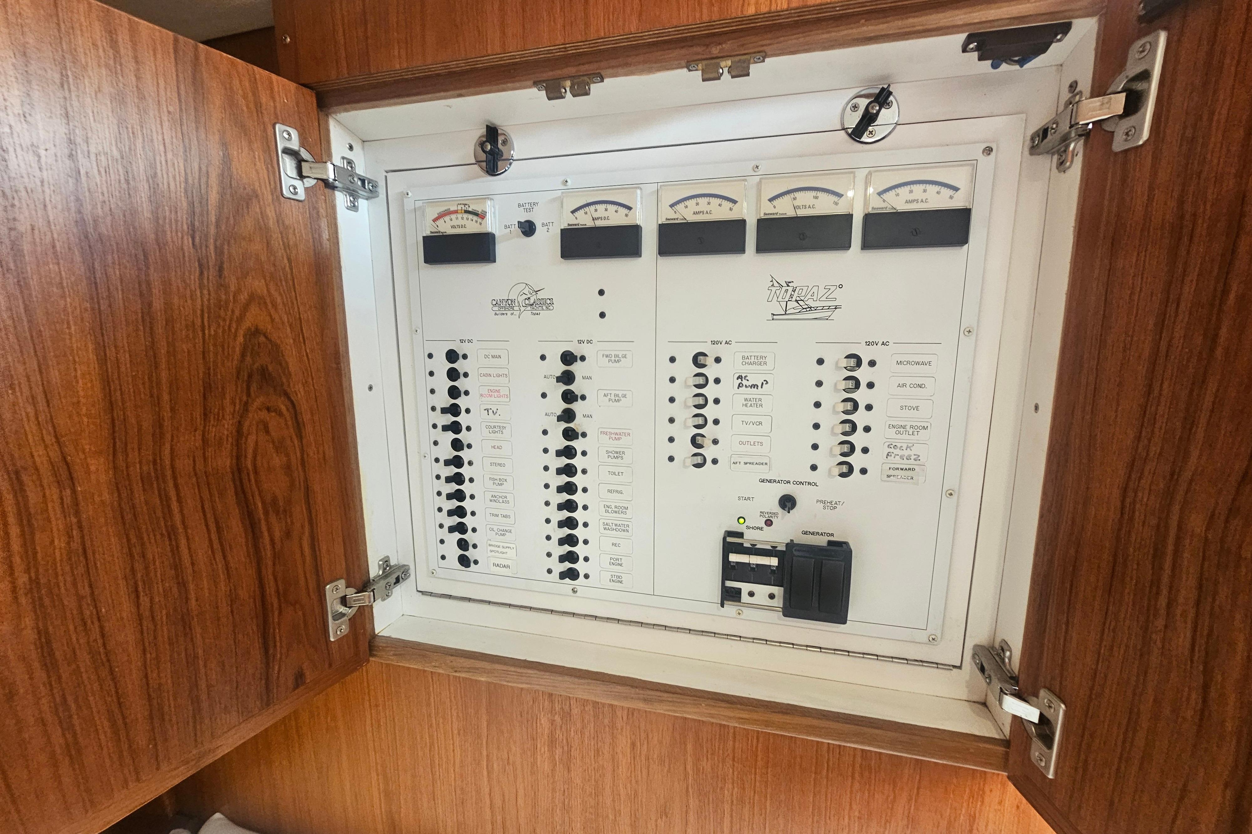 Electrical panel of a 2003 Topaz 32 Express boat with wooden cabinet doors.