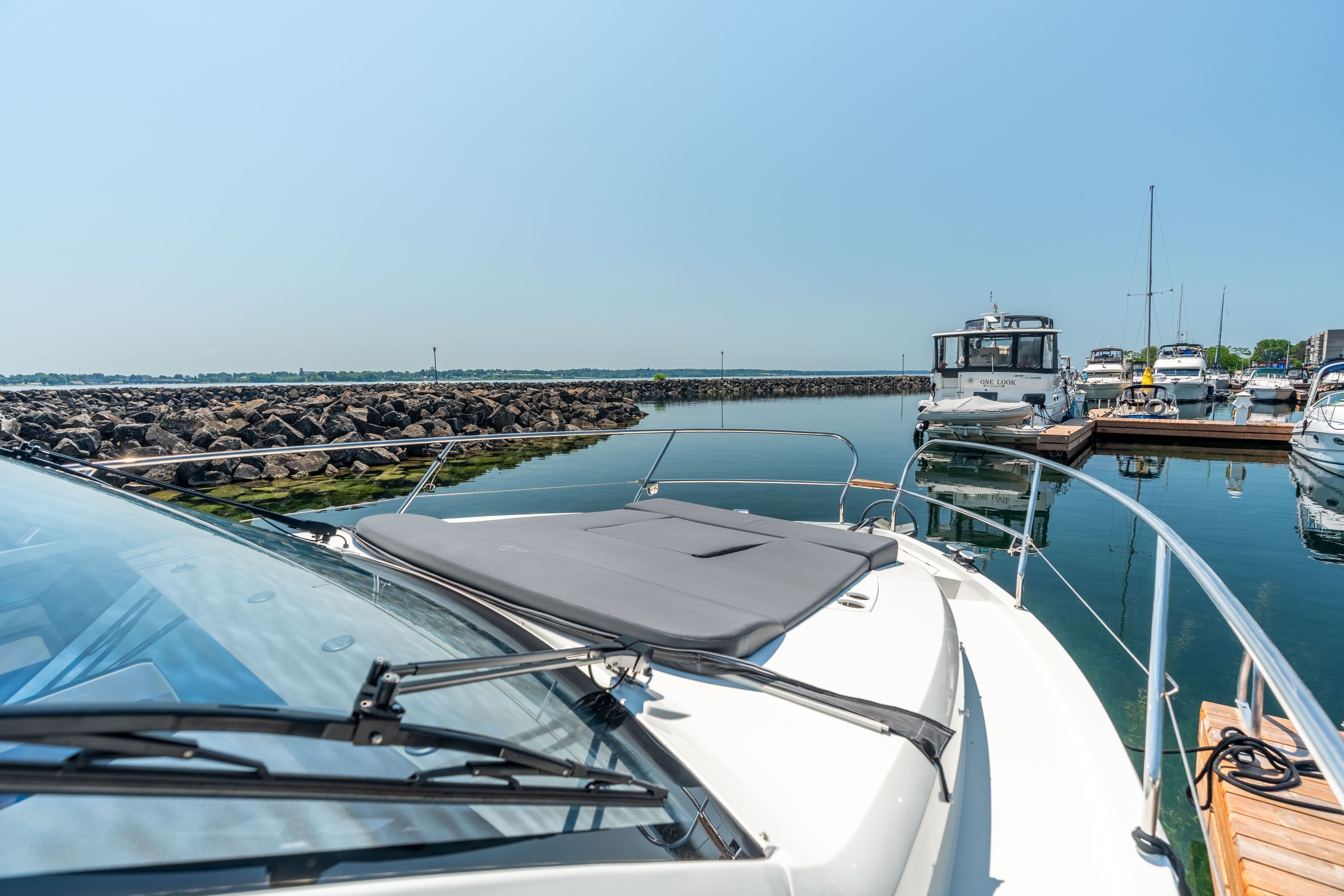 A Sealine C335V boat docked in a harbor, surrounded by calm water and other boats.