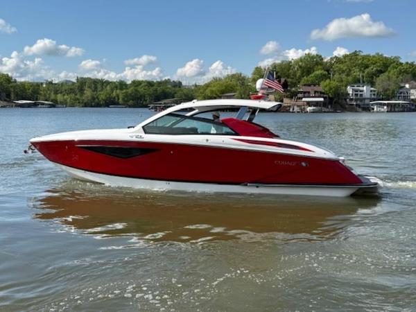 2022 Cobalt A36BR boat on a lake, red and white design, clear sky, scenic background.