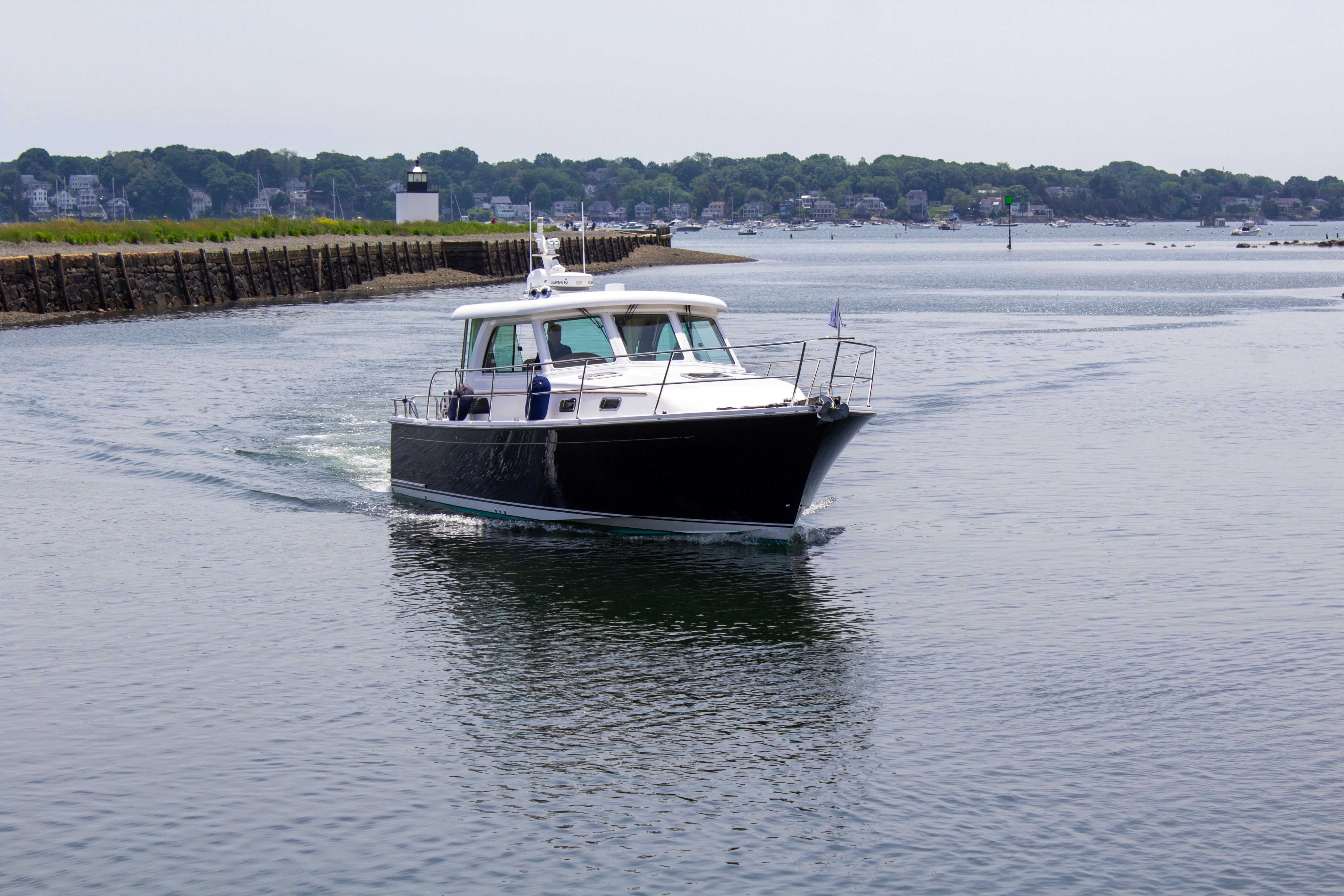 A sleek motorboat cruises on calm water, with a shoreline in the background.