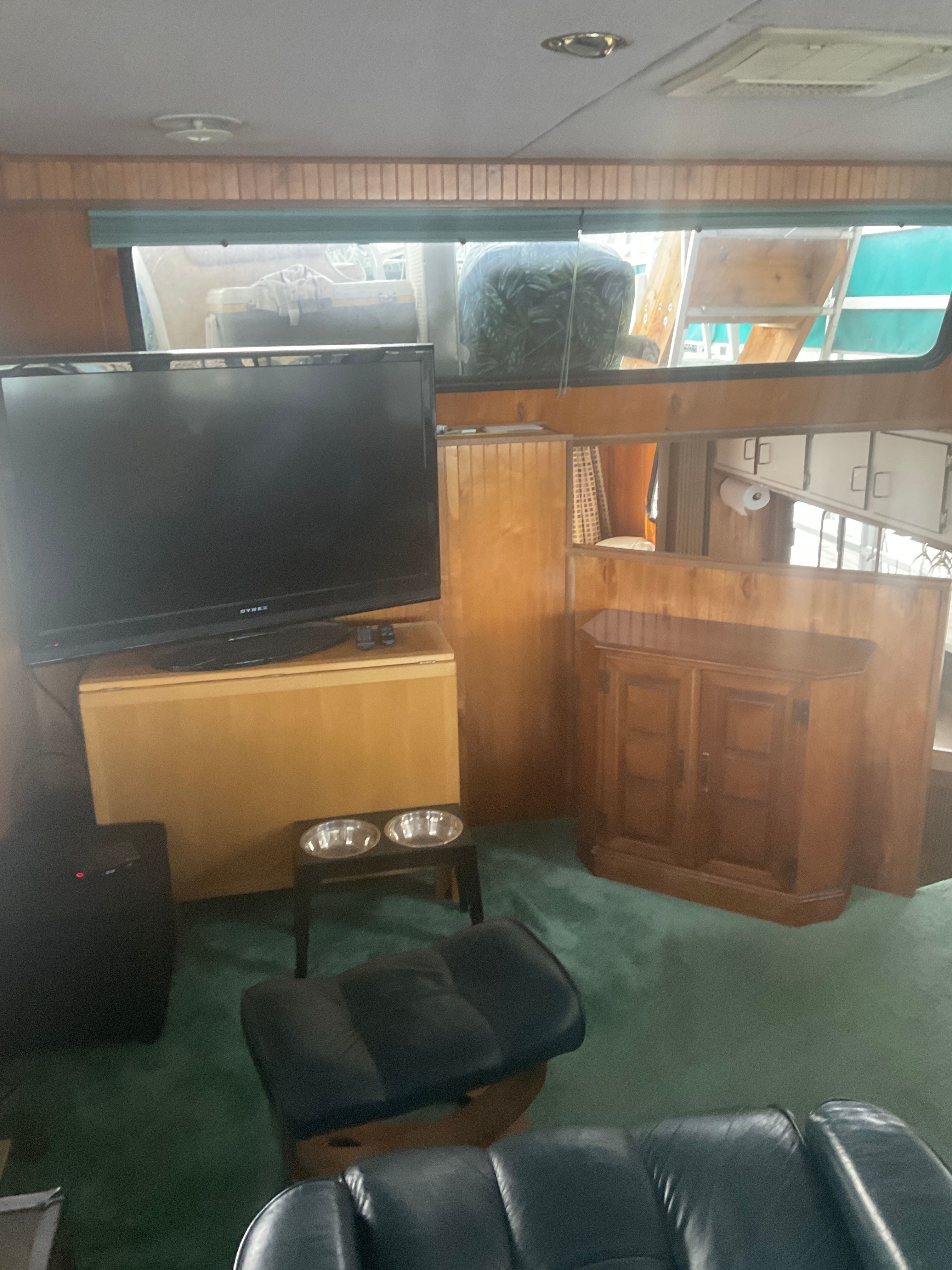 The interior of a 1996 Gibson 44 Standard features a TV, wooden cabinetry, and green carpeting.