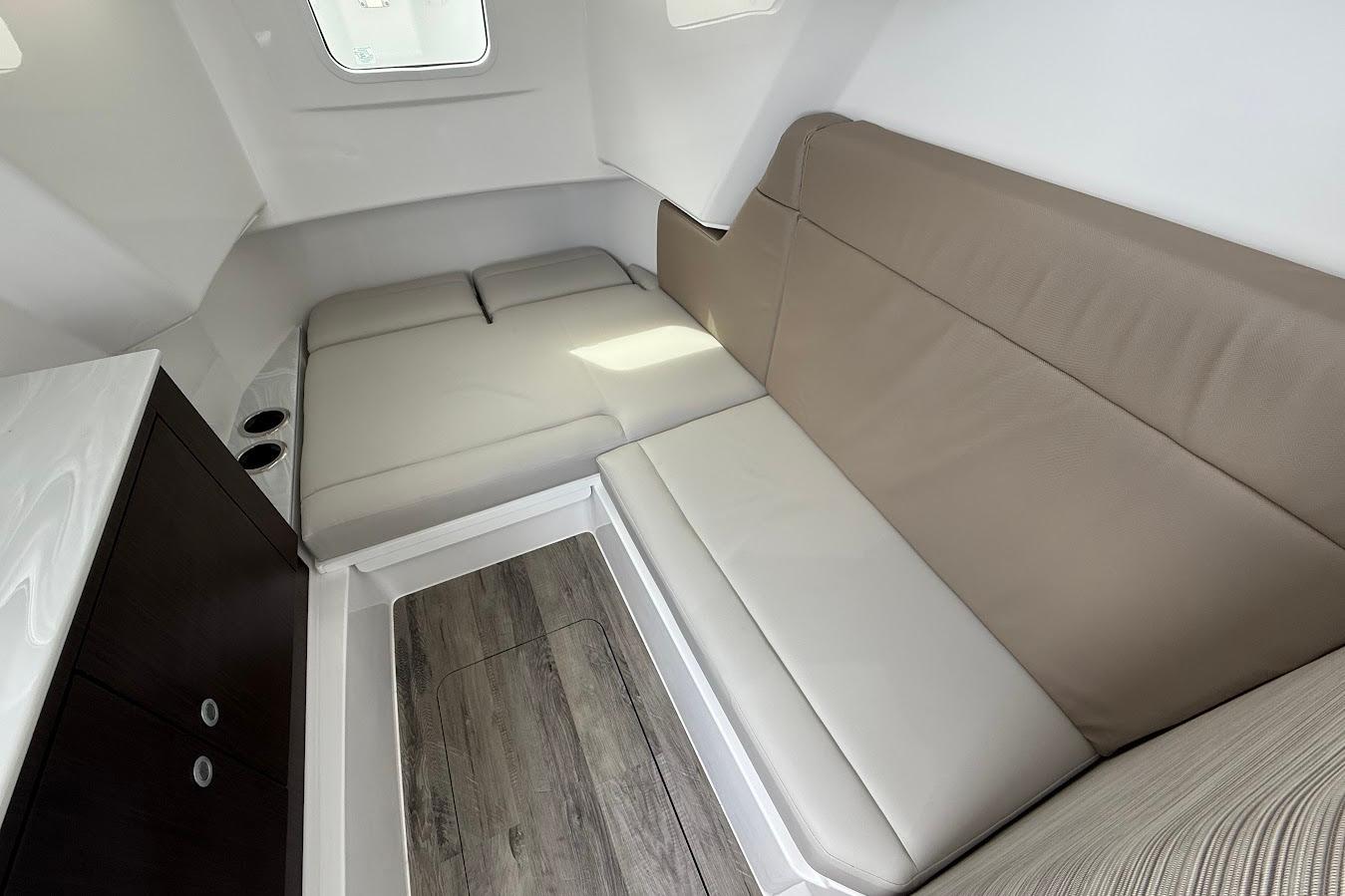 Interior cabin of 2026 Everglades 375 Center Console with beige seating and wood flooring.