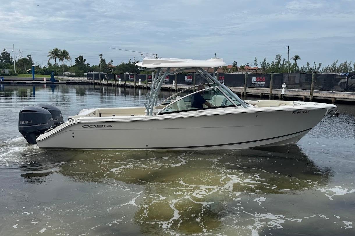 2020 Cobia 280 Dual Console boat on calm water near a marina.