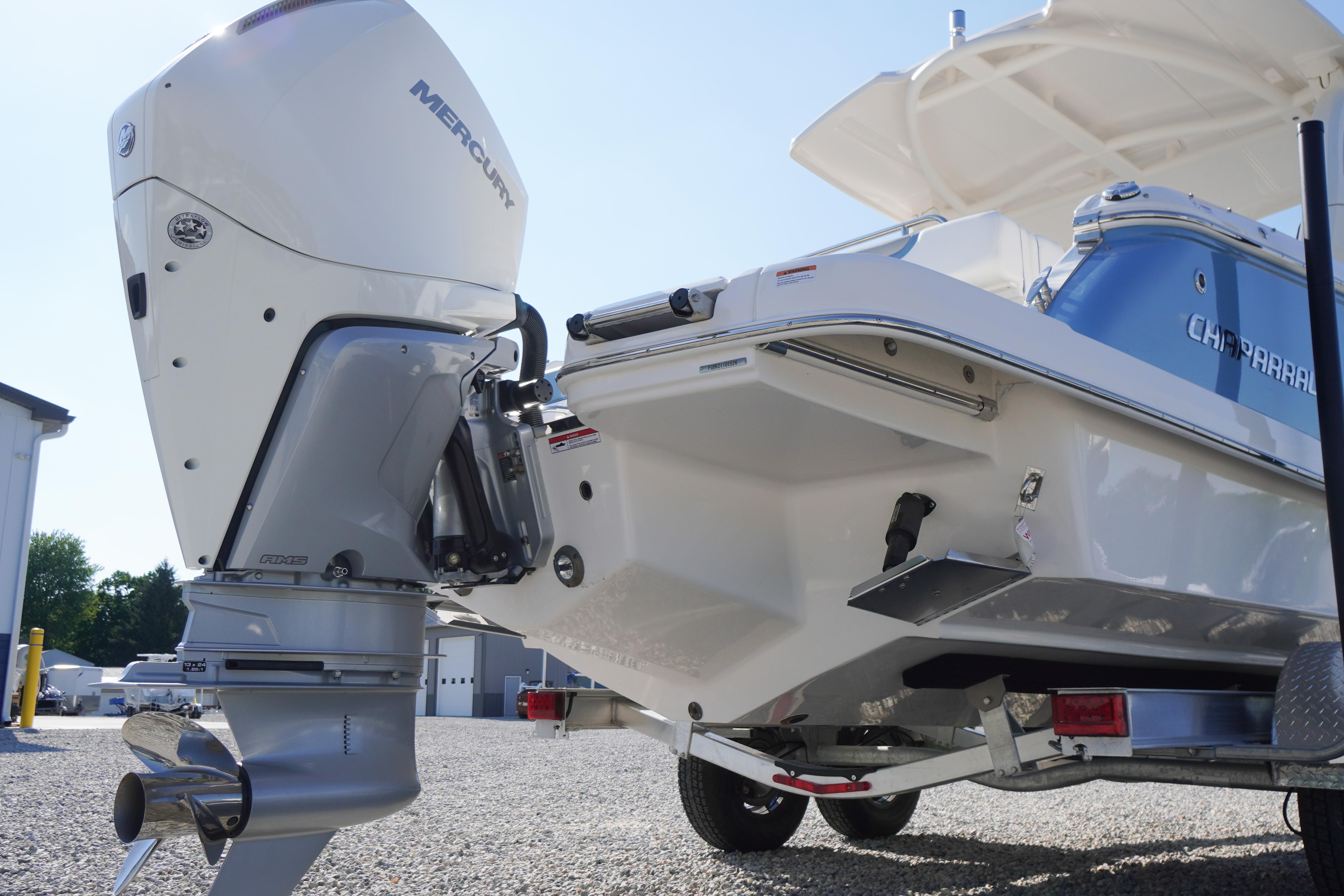 2026 Chaparral 270 OSX boat with Mercury outboard engine, parked on gravel.