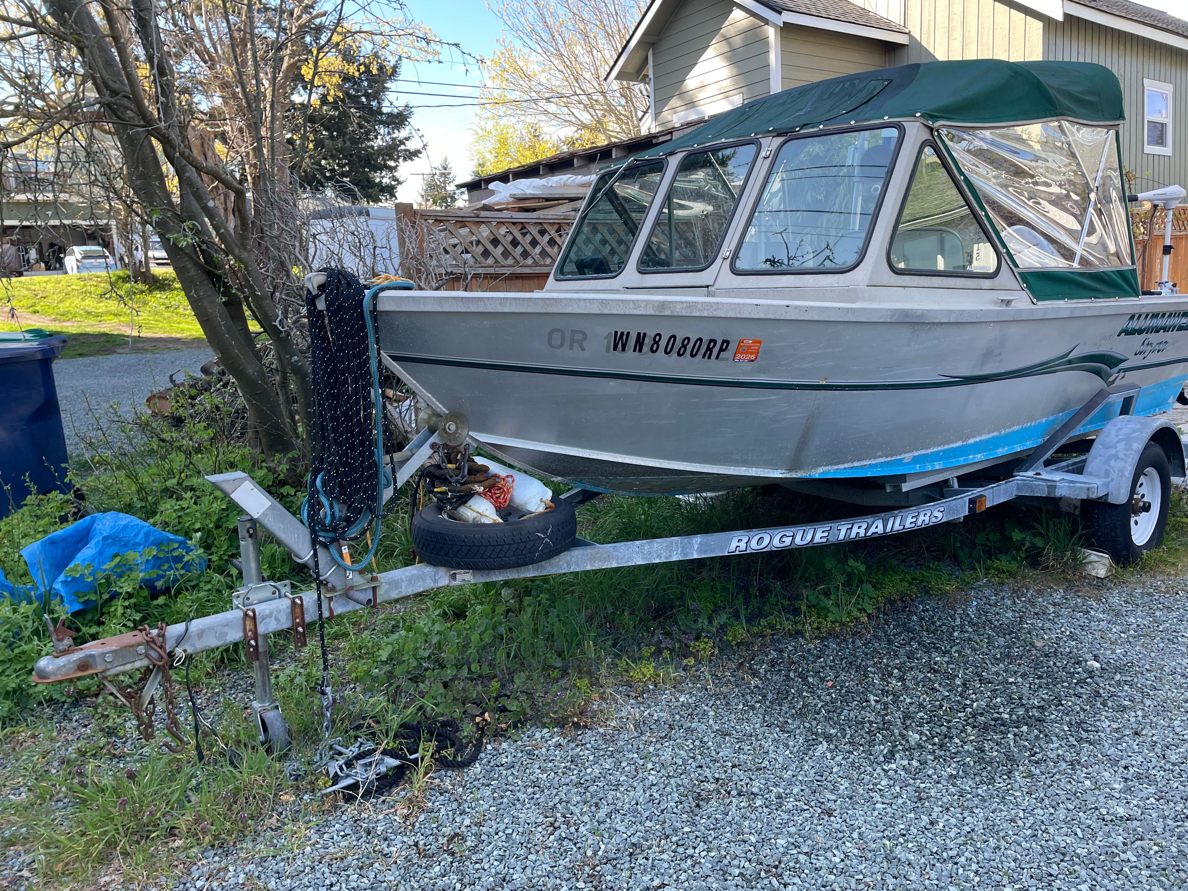 A 2001 Alumaweld Stryker boat is on a trailer in a yard.