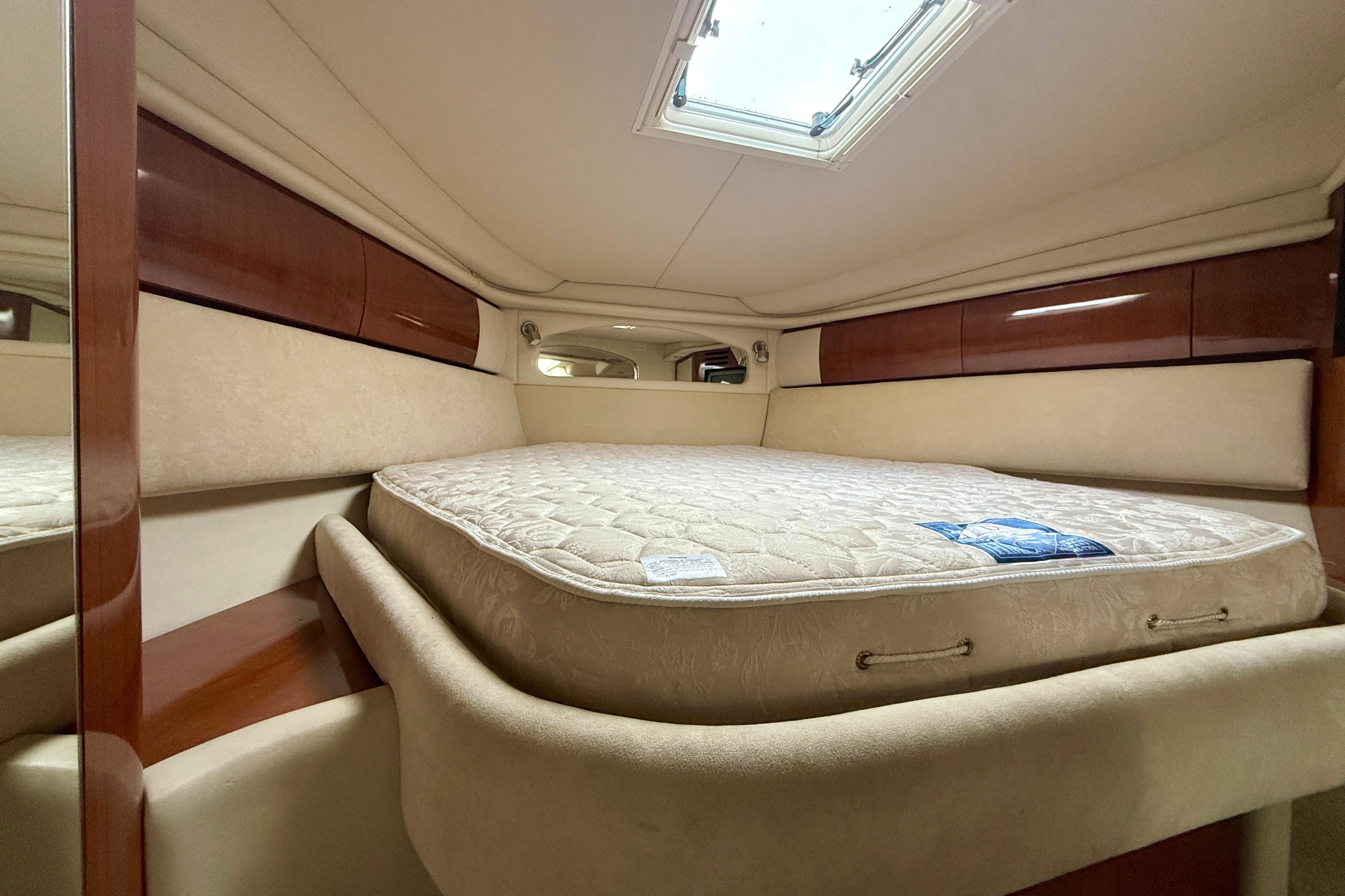 Interior cabin of 2004 Searay 360 Sundancer with bed and wooden accents.