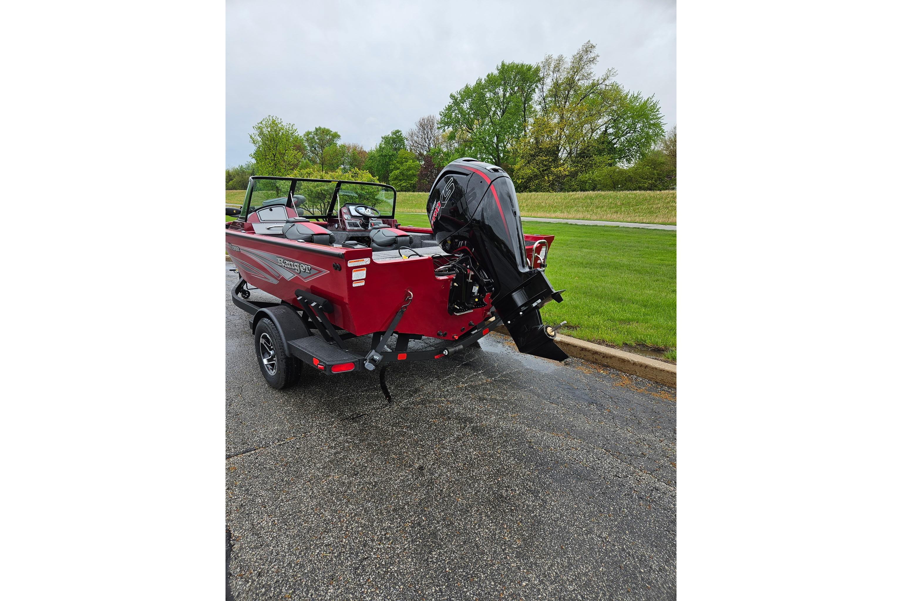 2026 Ranger VS1782SC Reata boat with outboard motor on a trailer, parked on wet pavement.