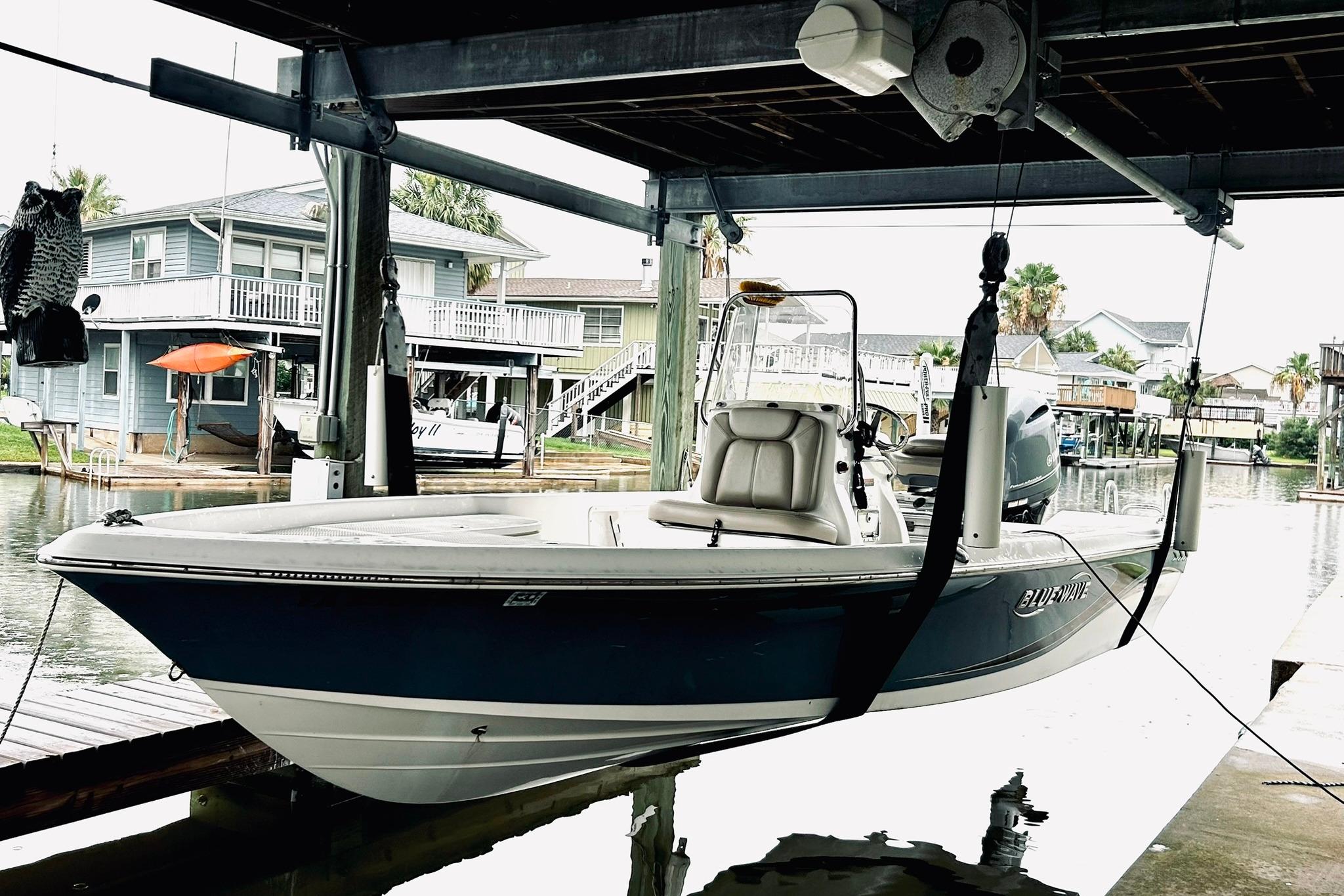 2017 Blue Wave 2200 PureBay boat suspended in a dockside lift.