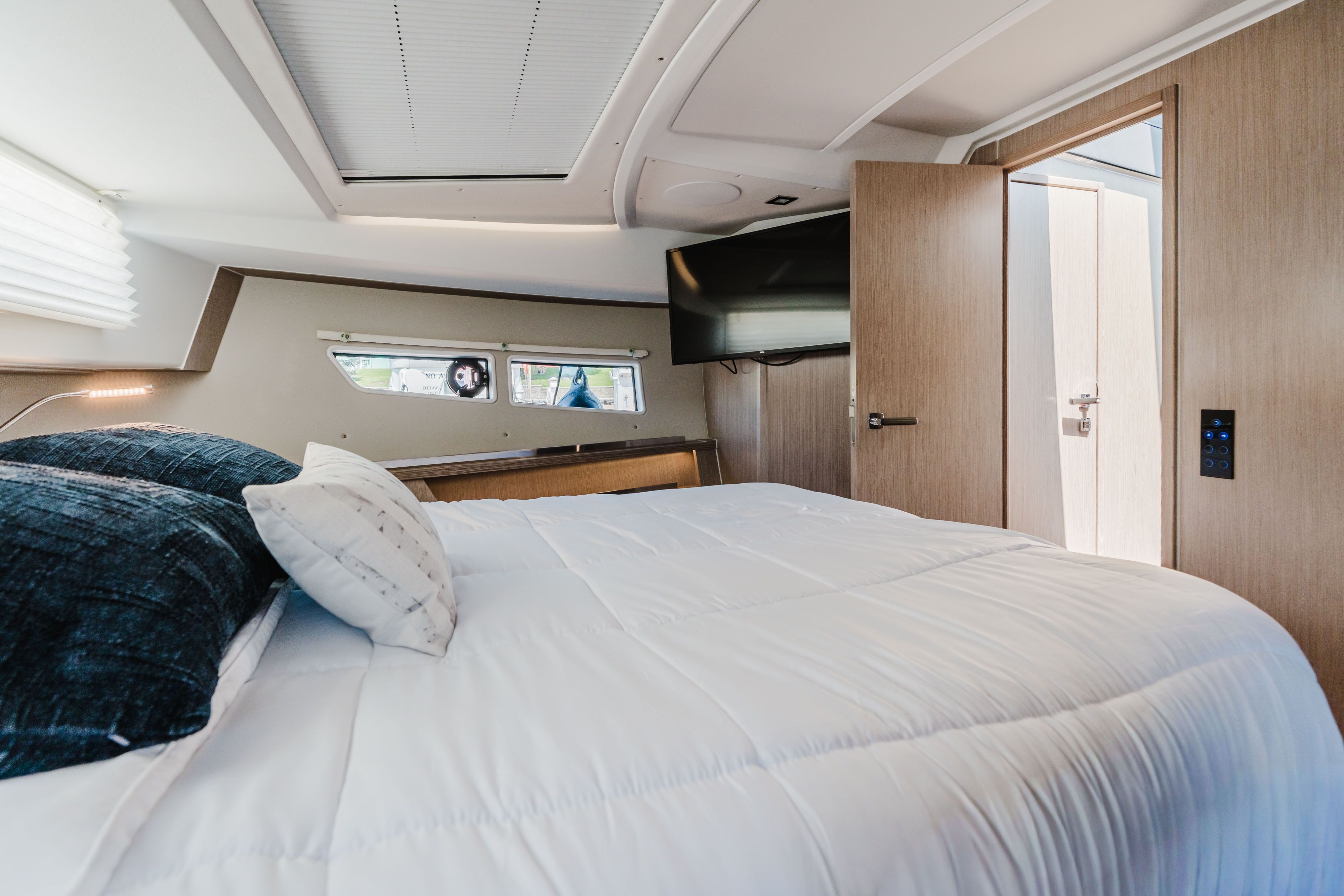 The image shows a modern cabin with a large bed and an adjoining bathroom.