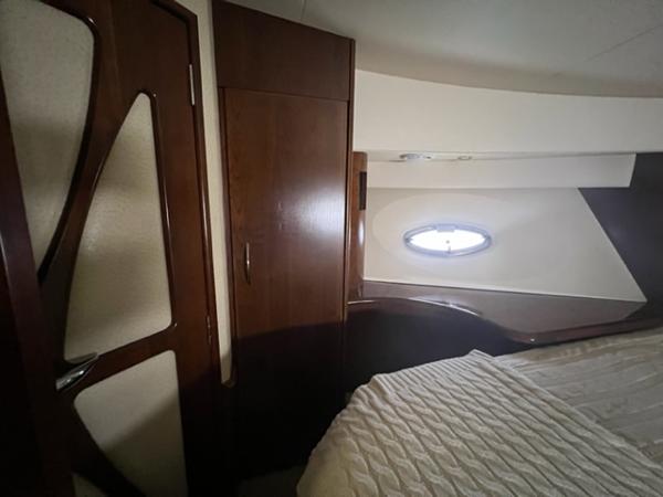 Interior cabin of a 2009 Ovation 52 yacht with wooden cabinetry and a porthole window.