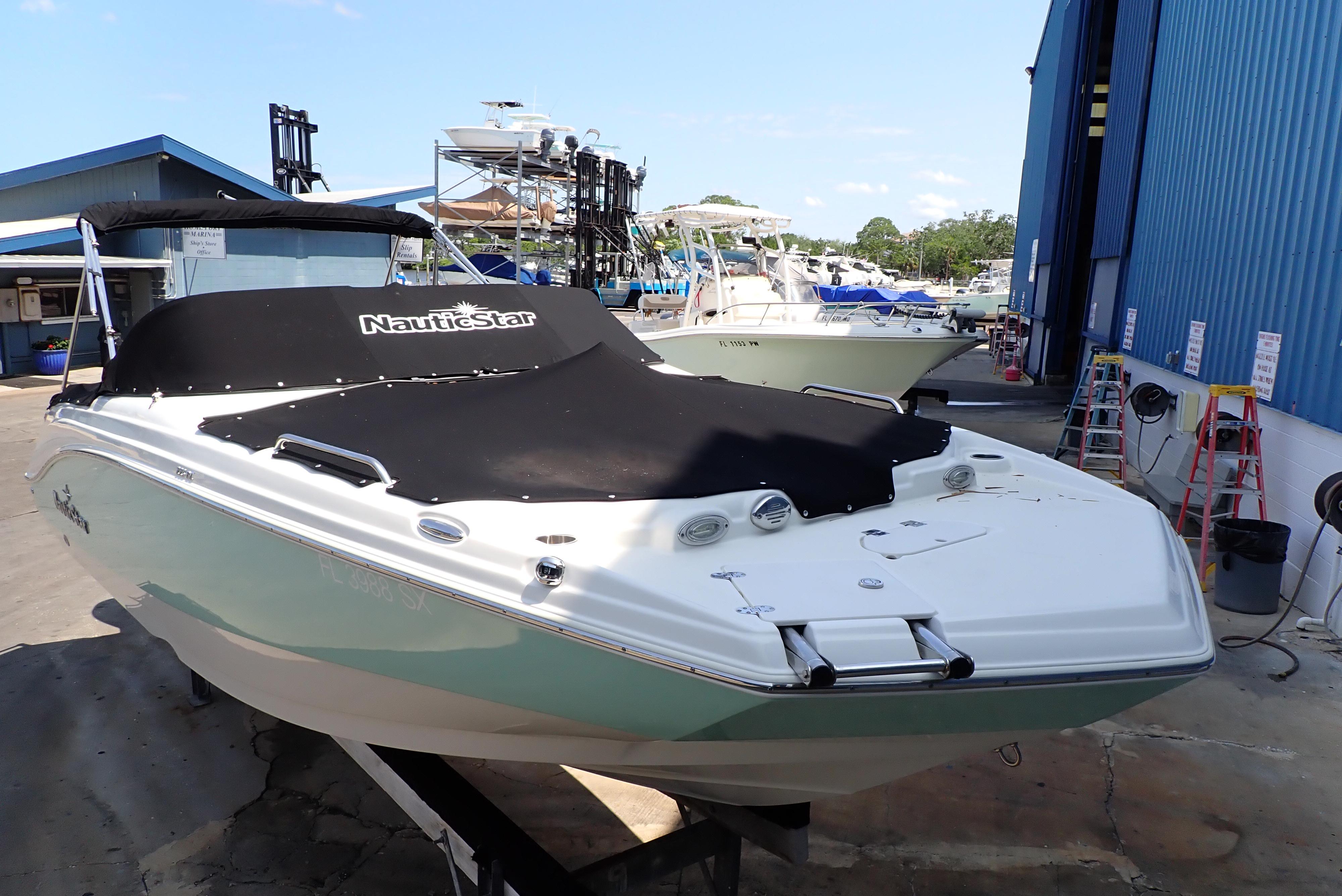 2021 NauticStar 223 DC boat with cover, docked at a marina.