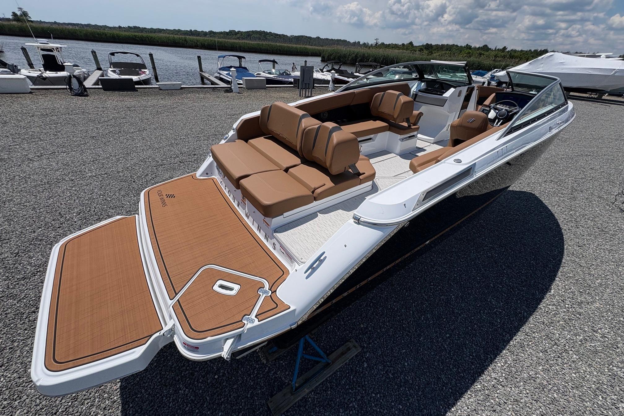 2026 Four Winns H6 boat with spacious seating, docked near a serene waterfront.
