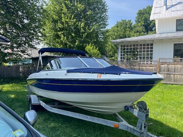 A 2007 Bayliner 185 boat on a trailer in a grassy yard.