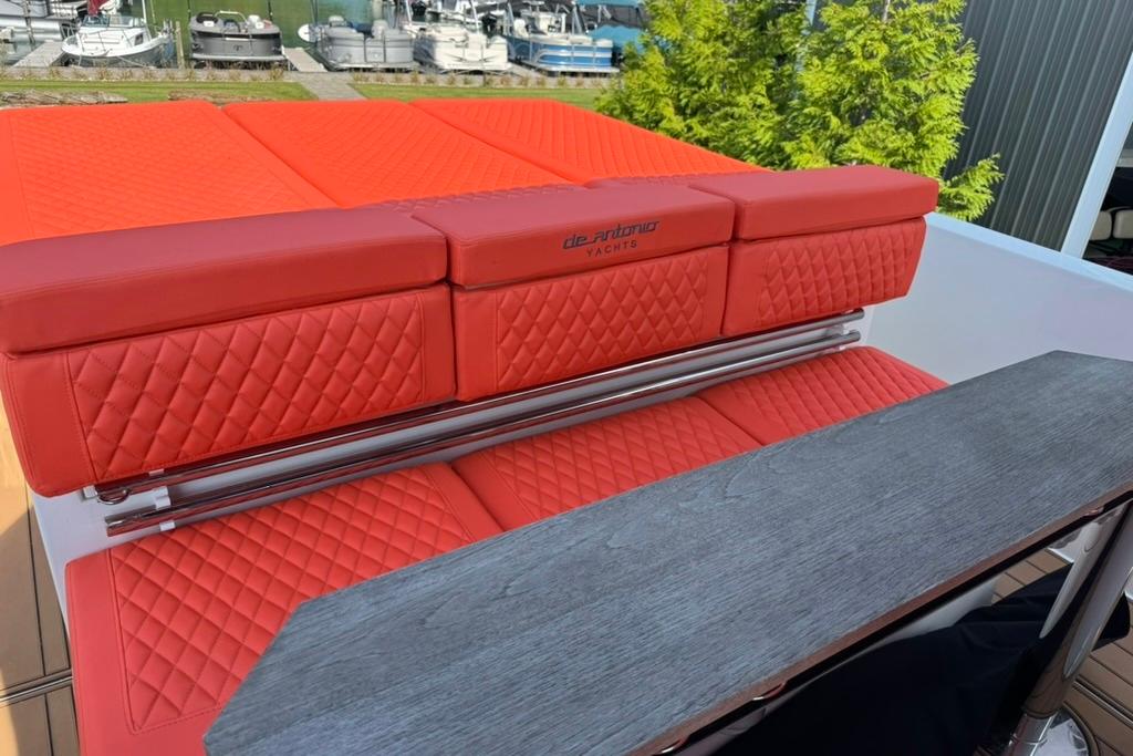 Red quilted seating on 2020 De Antonio Yachts D28, docked with boats in background.